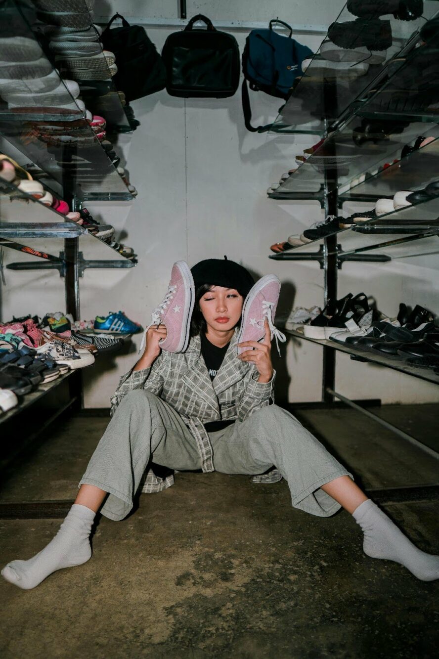 Hip girl in closet showing all her shoes and handbags.