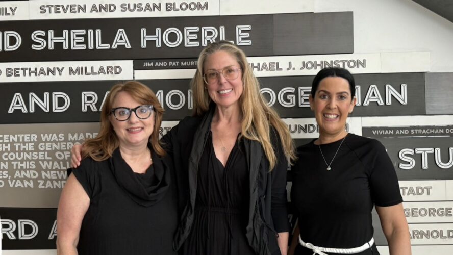 Melissa Shea, Susanna Moyer and Deborah Cantor smile and pose together for a picture in front of a wall at Parsons University.