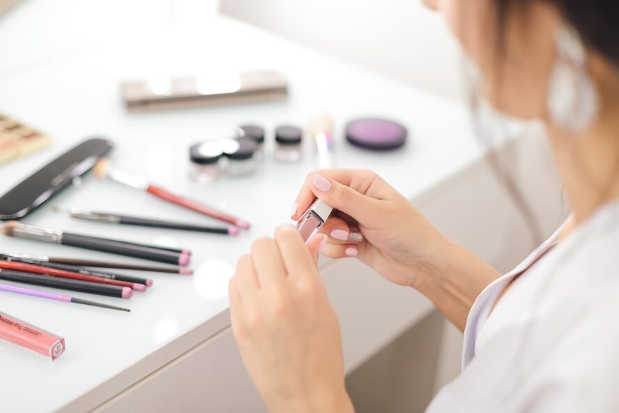 Woman using makeup and having her makeup lined up on a table.