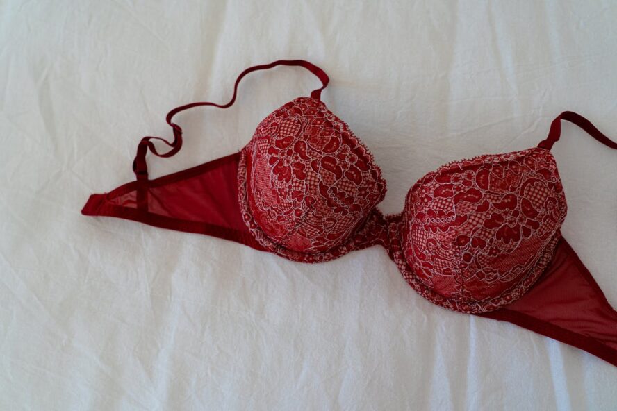 red lace bra laying on a white sheet.