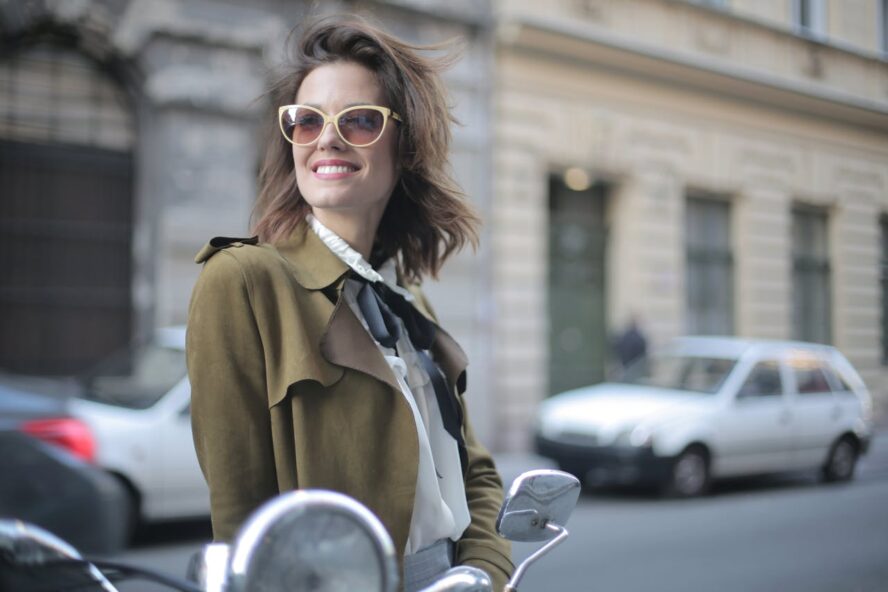 Smiling woman standing on the street wearing sunglasses.