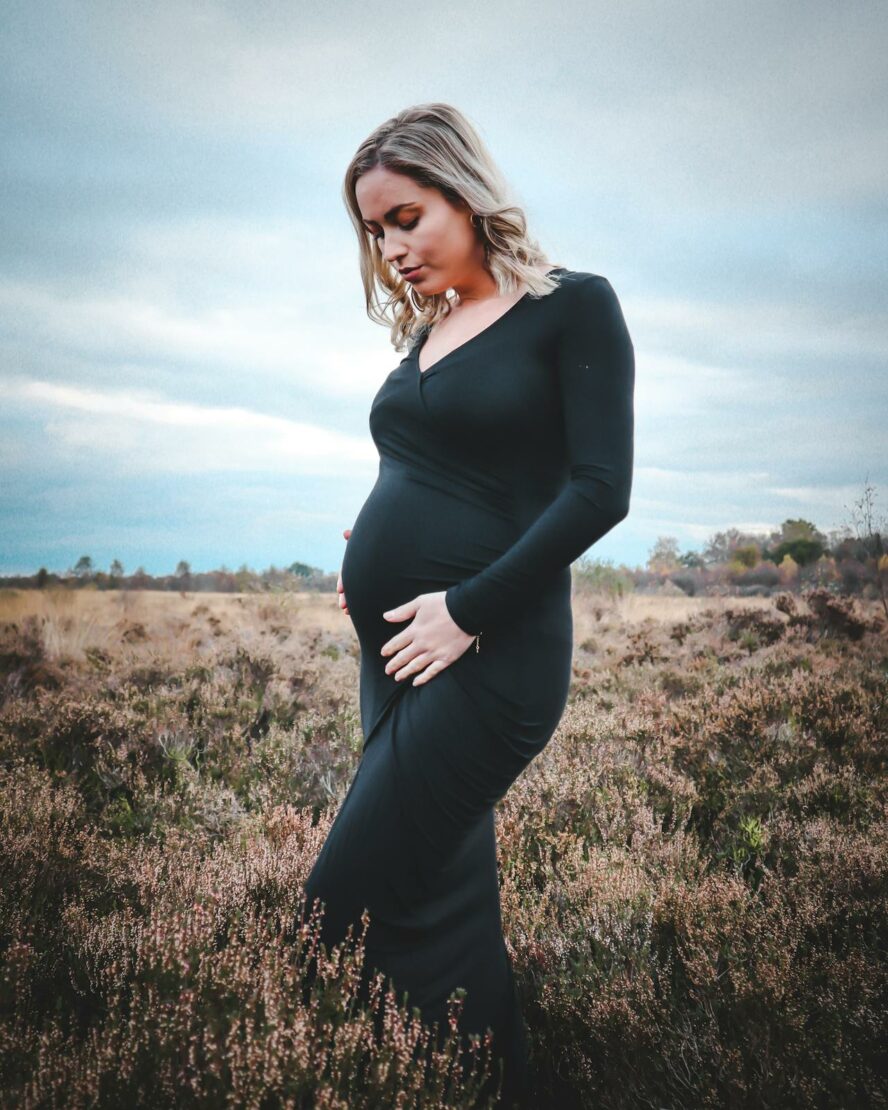 A pregnant woman in a tight fitting fashionable dress.