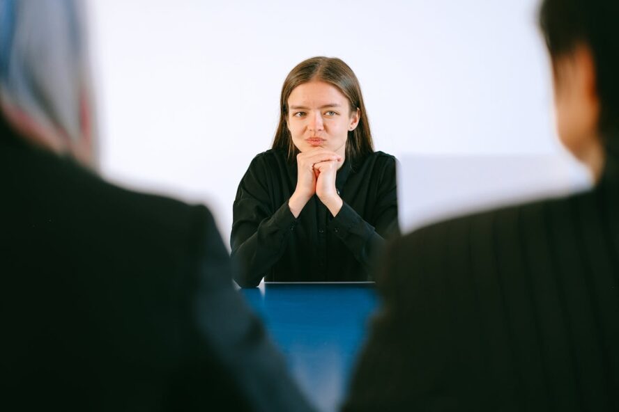 Young woman in thought at a meeting with two other people.