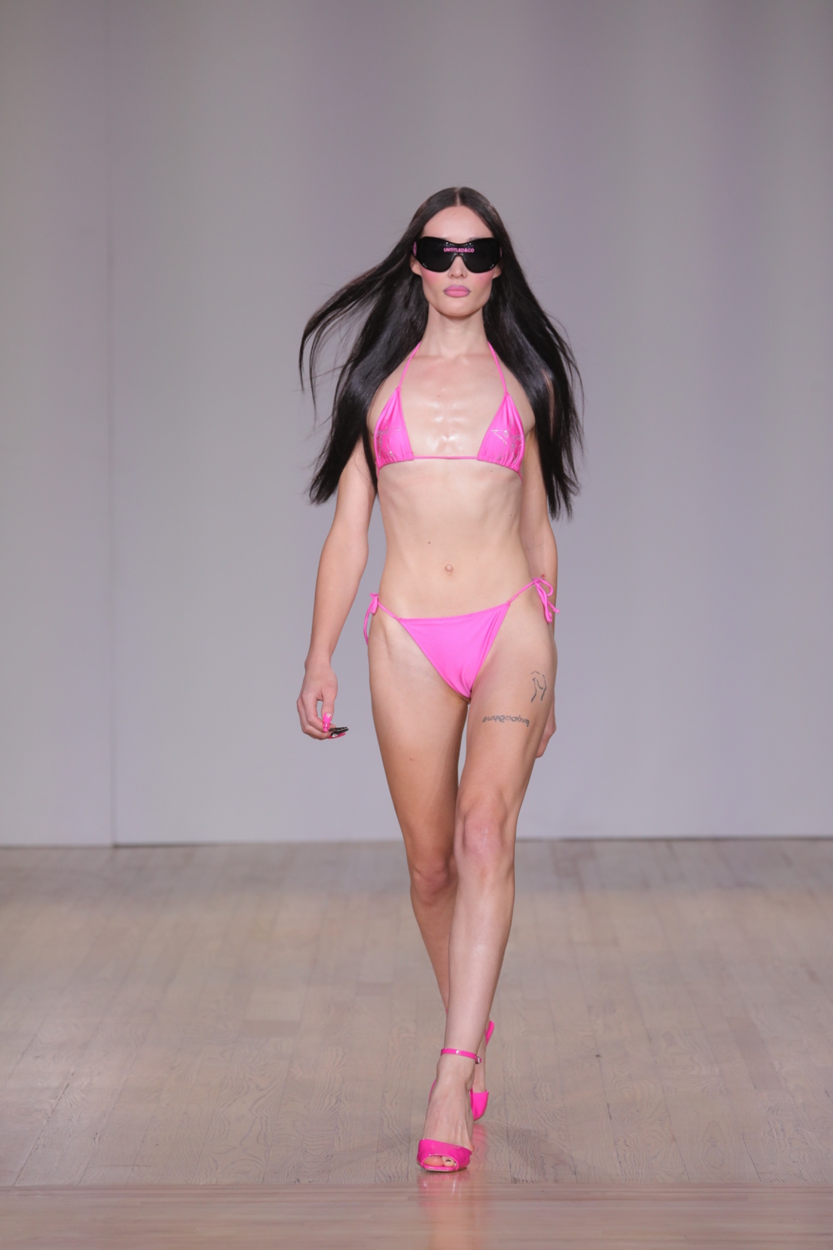 A model walking the runway wearing a pink bikini.