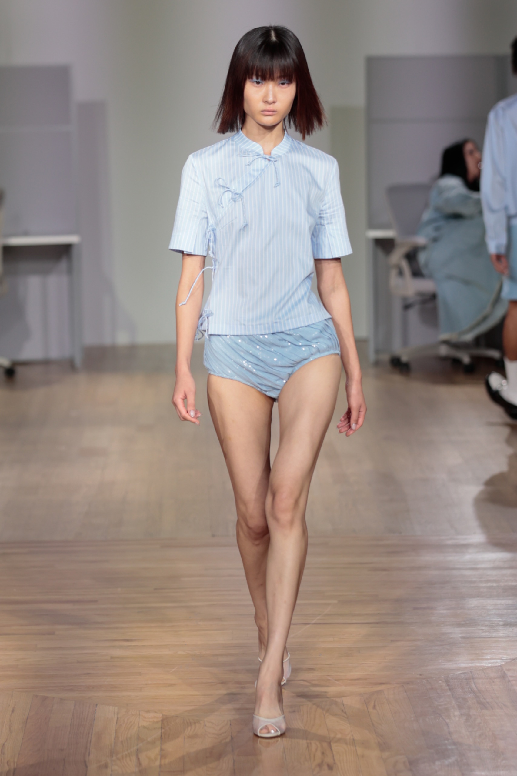 A model walking the runway wearing a blue t-shirt and shorts.