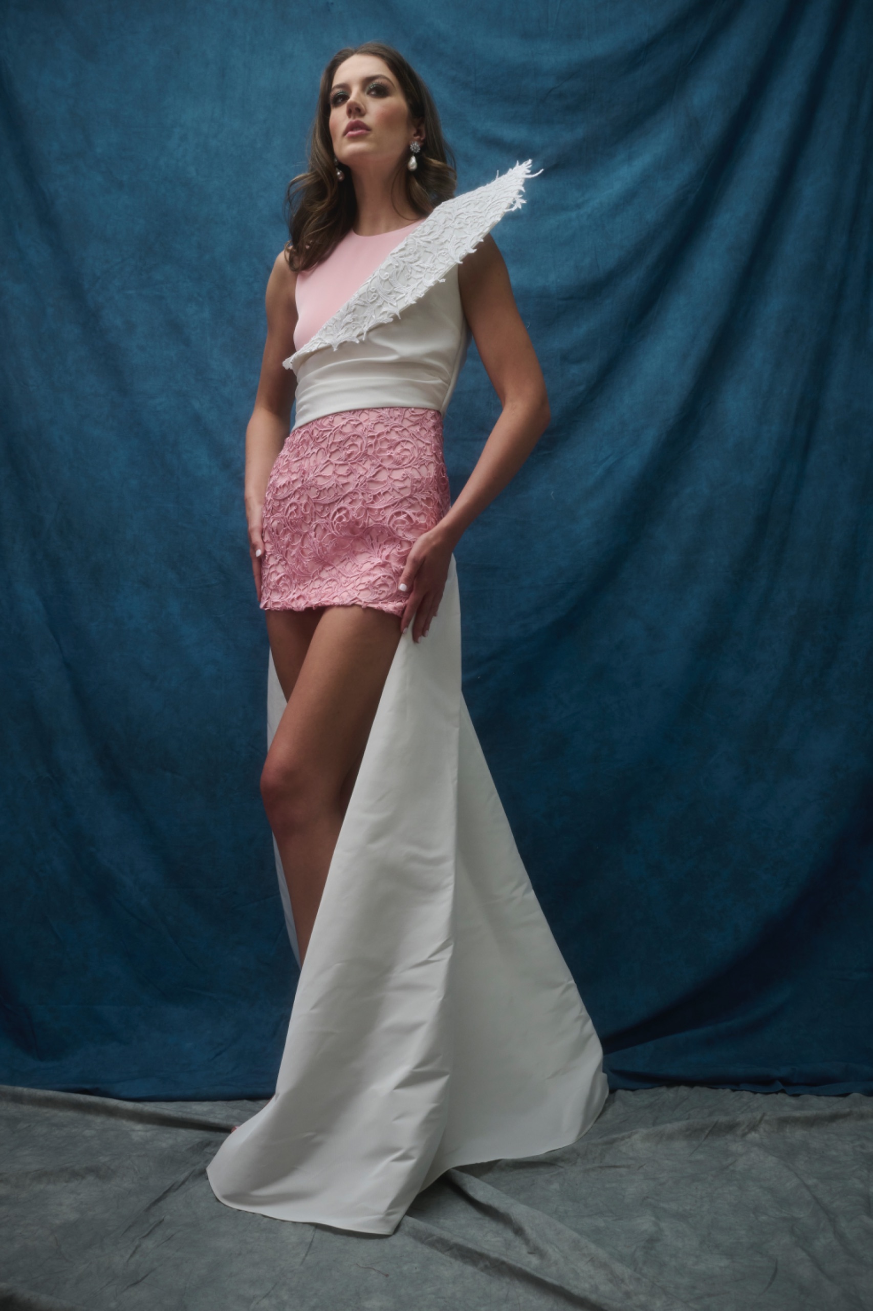 A model wearing a white top and pink skirt.