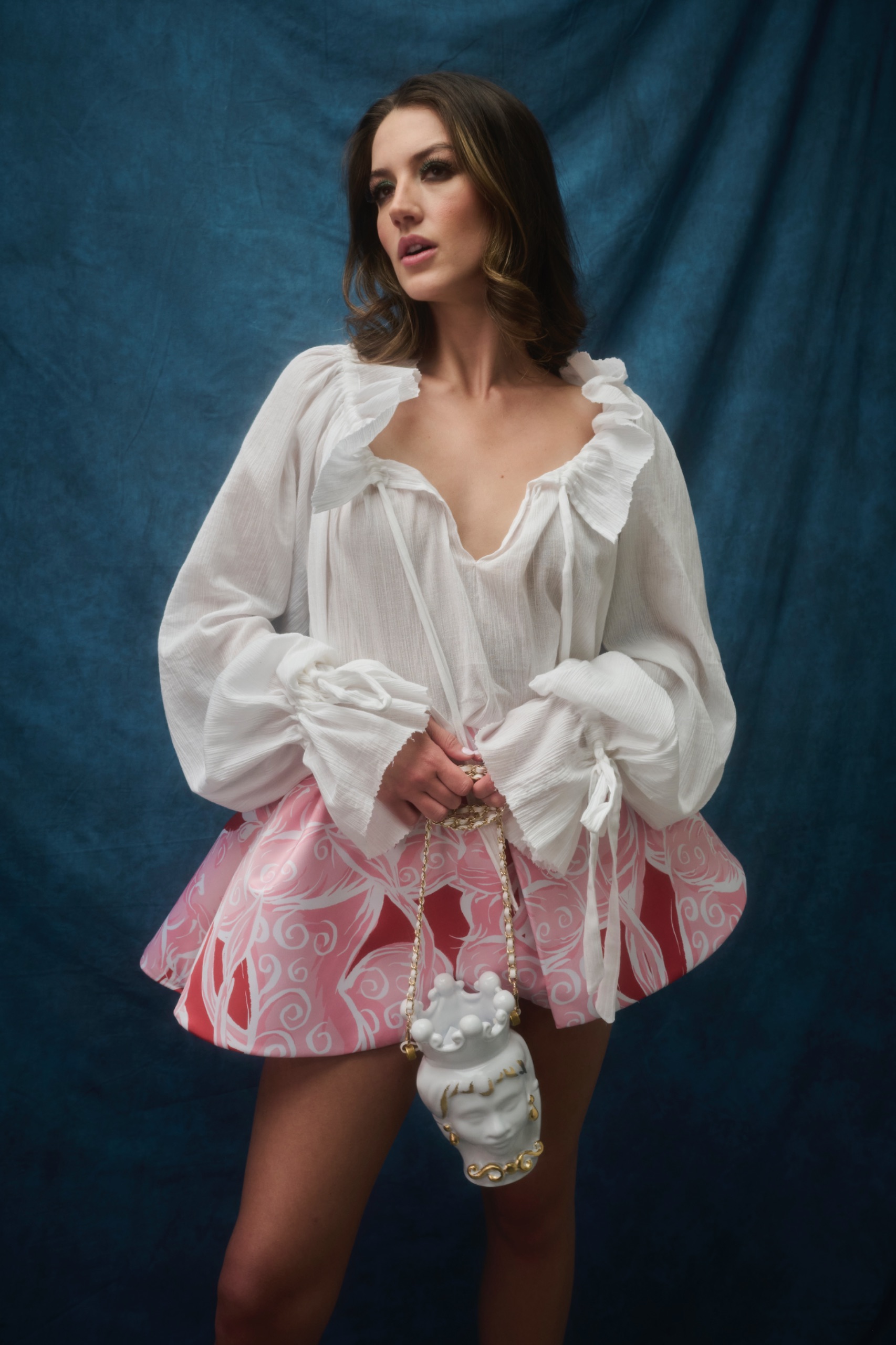 A model wearing a white top and pink skirt.