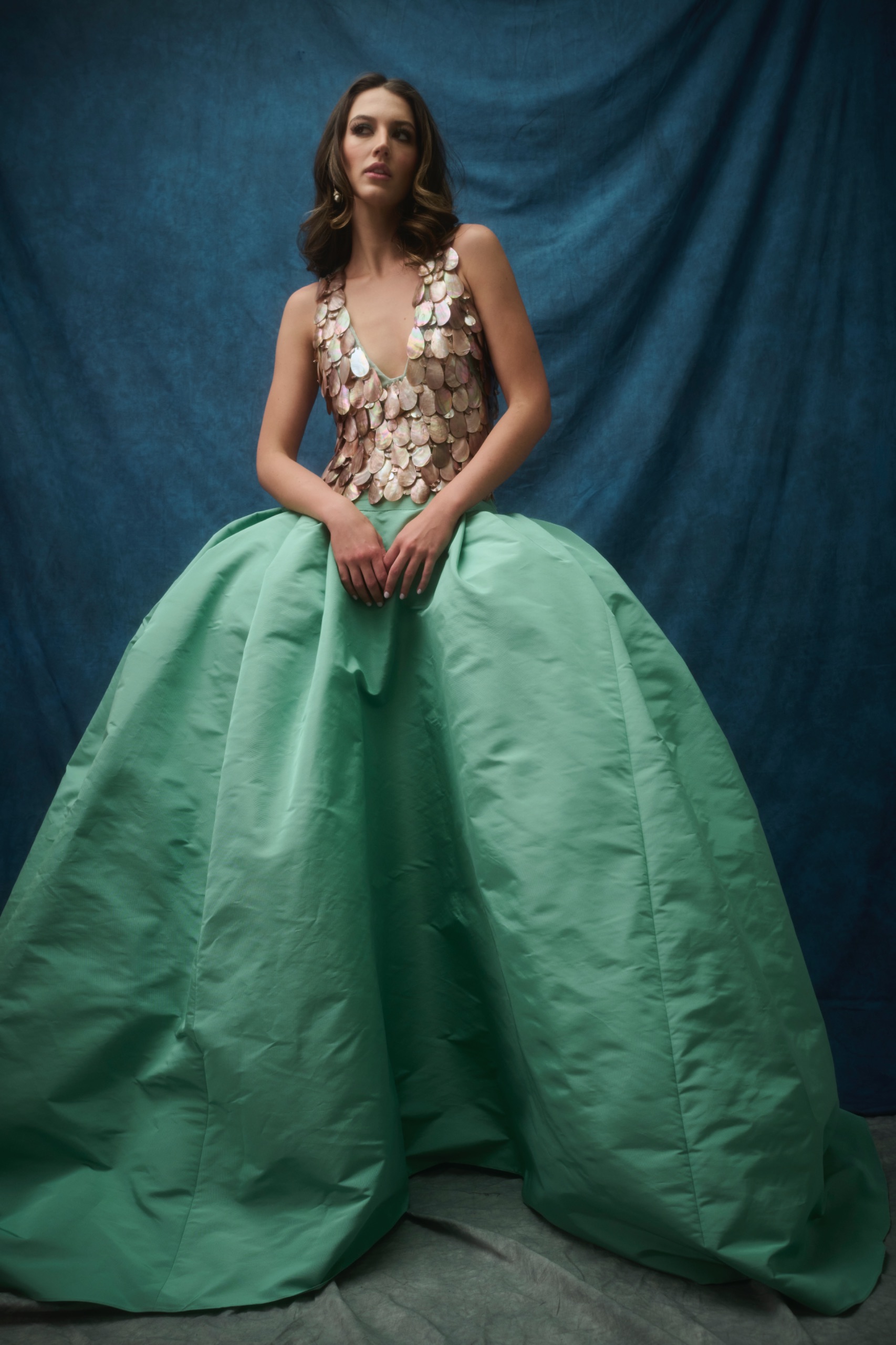 A model wearing a green and silver dress.