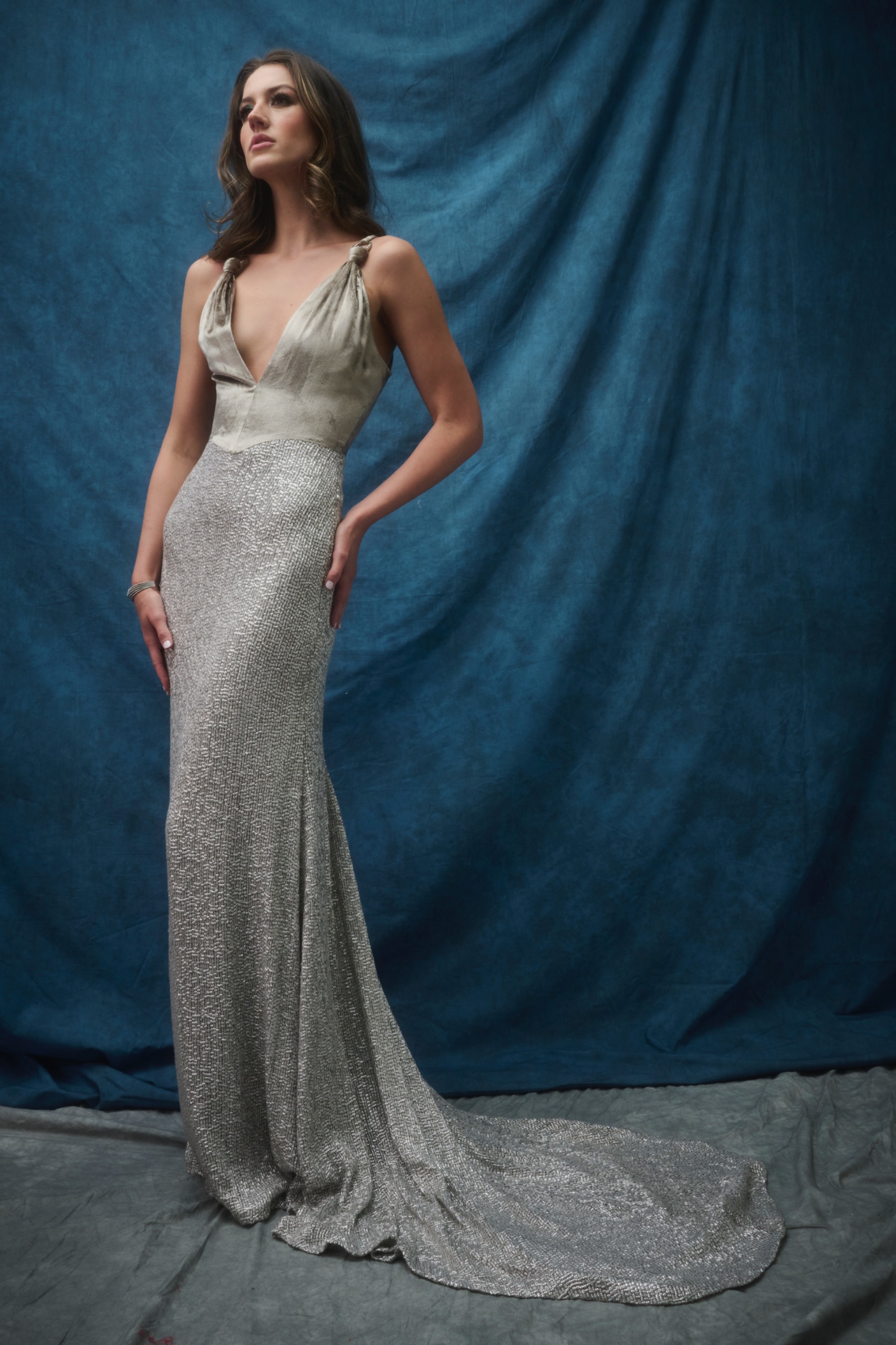 A model wearing a long silver dress.