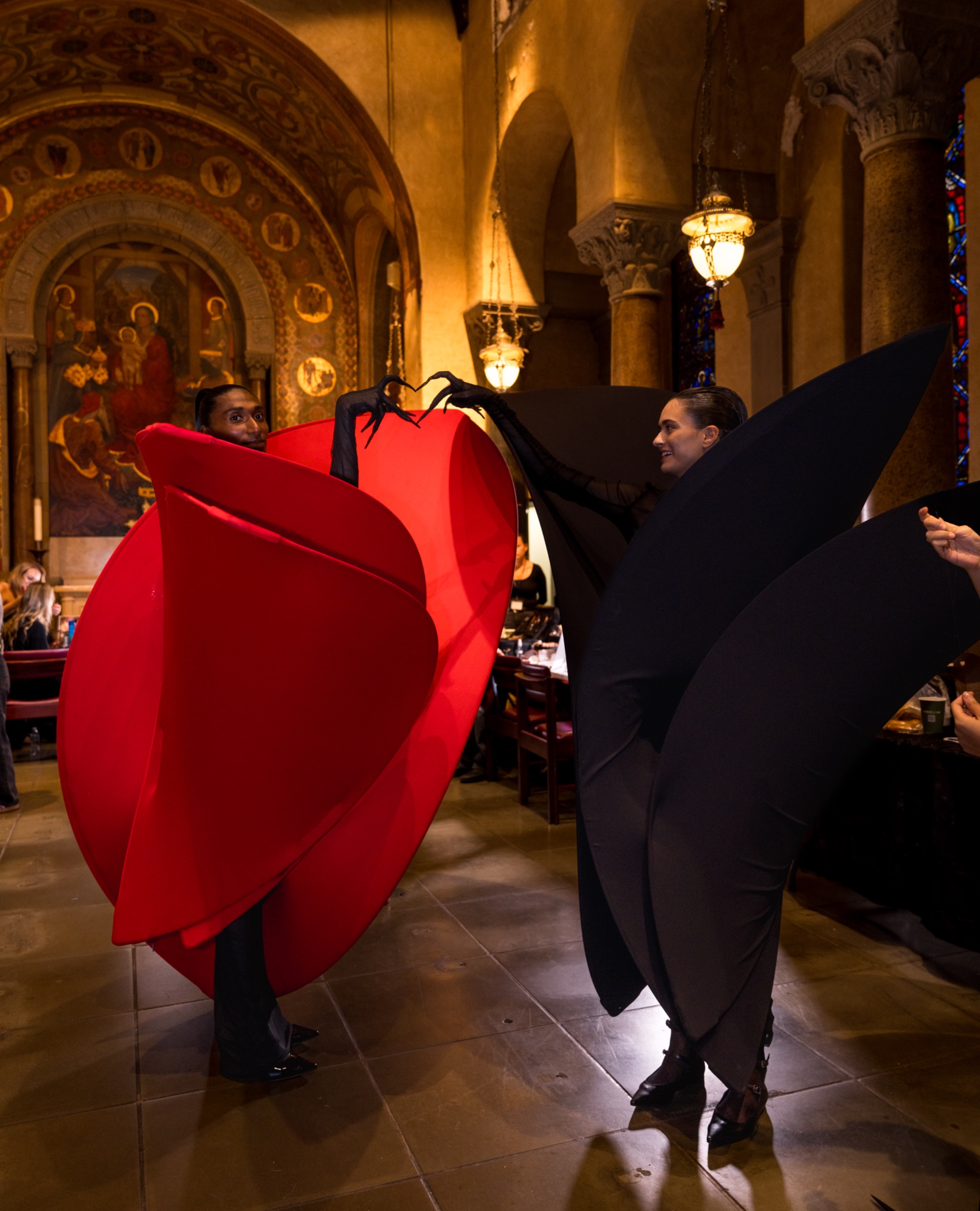 Two models wearing a black dress and a red dress with black gloves.