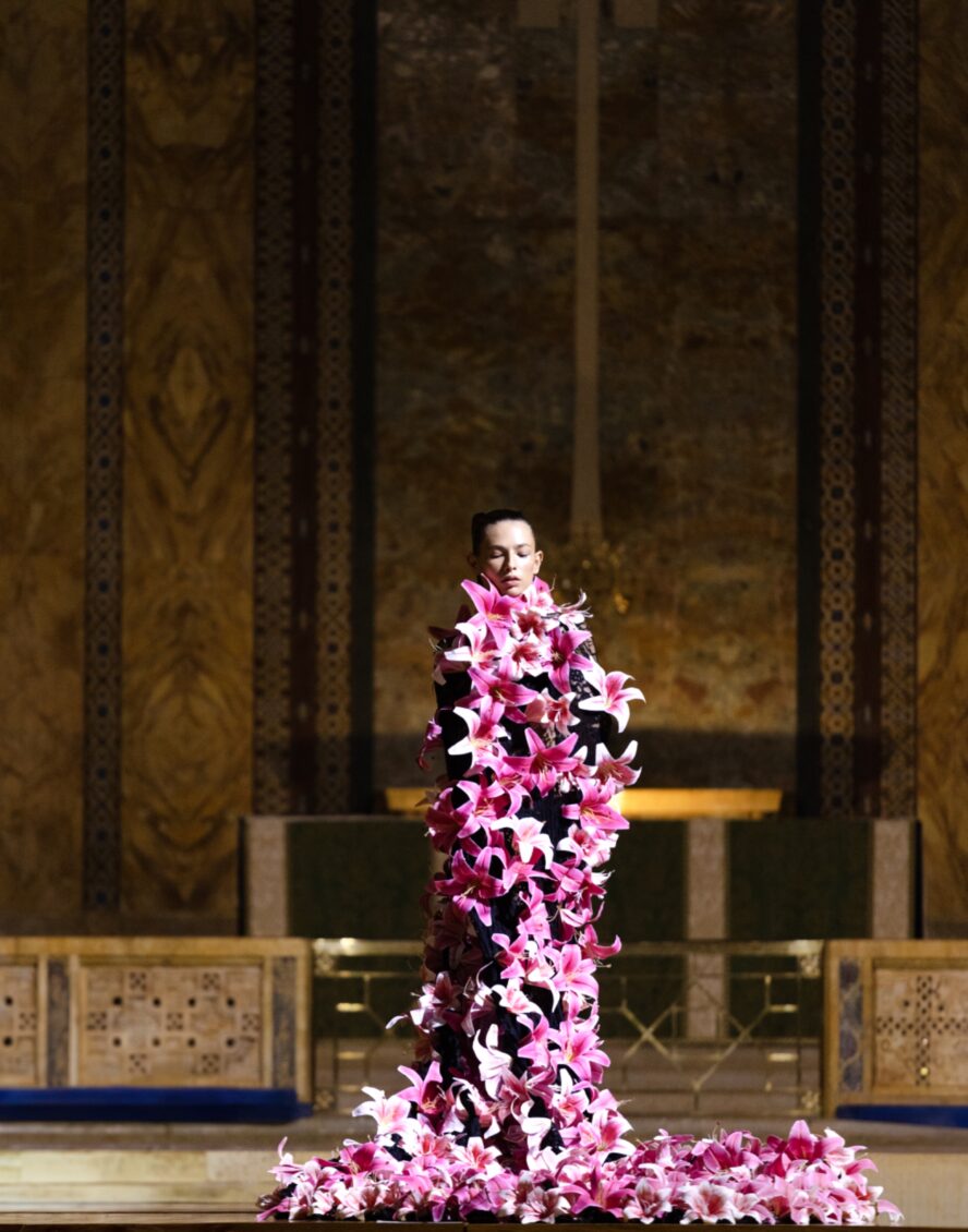 A model wearing a black dress with pink and white lilies.