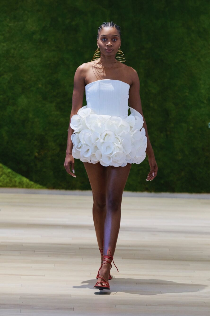 A model walking the runway wearing a short white dress.