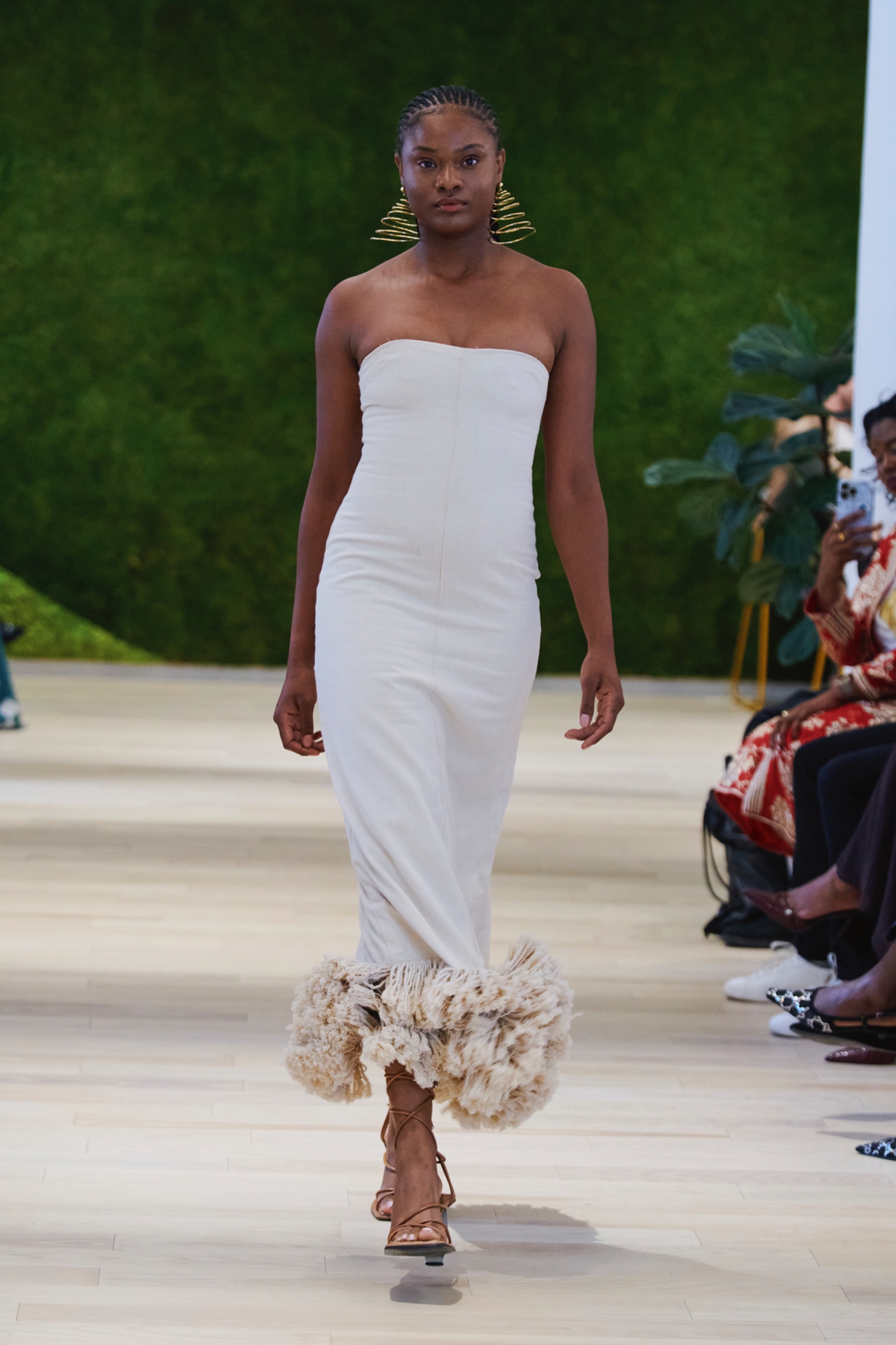 A model walking the runway wearing a long white dress.