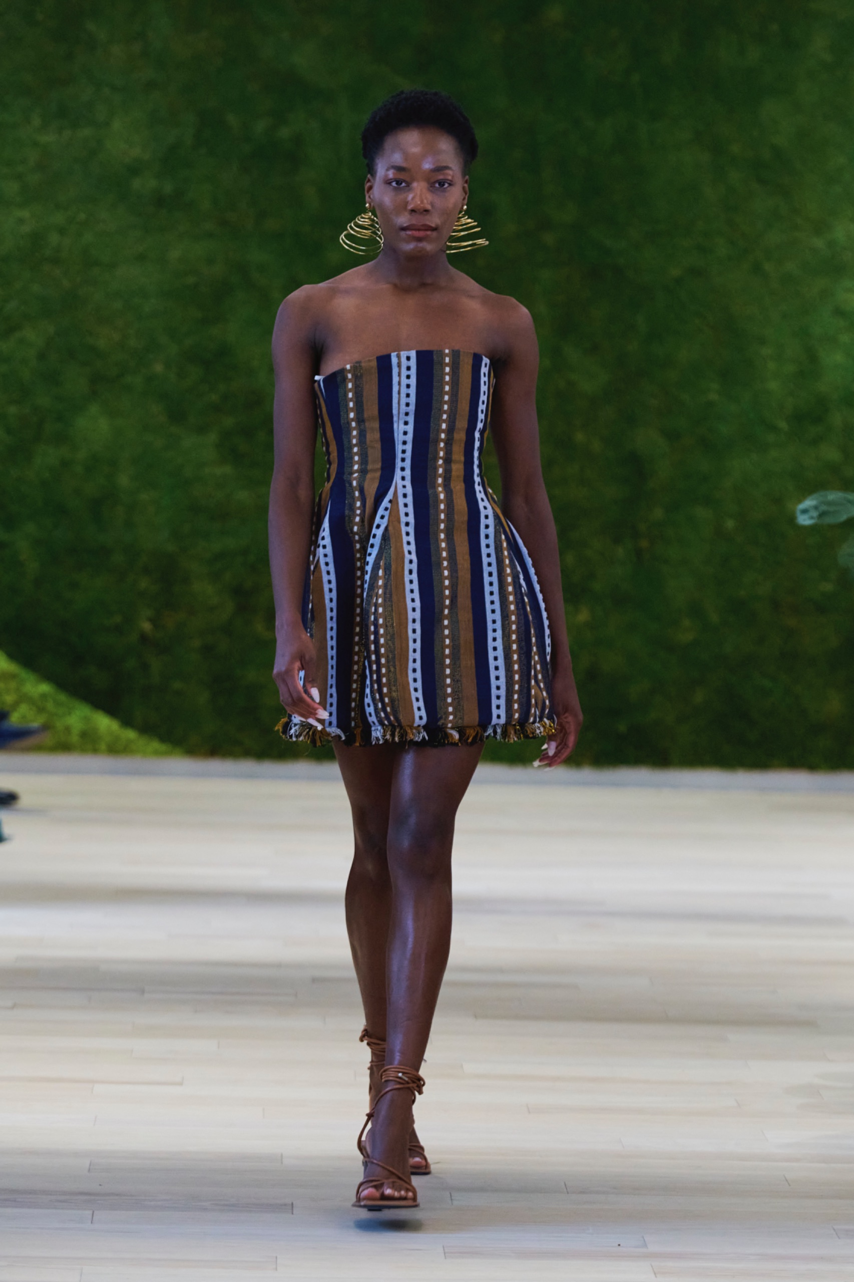 A model walking the runway wearing a blue striped dress.