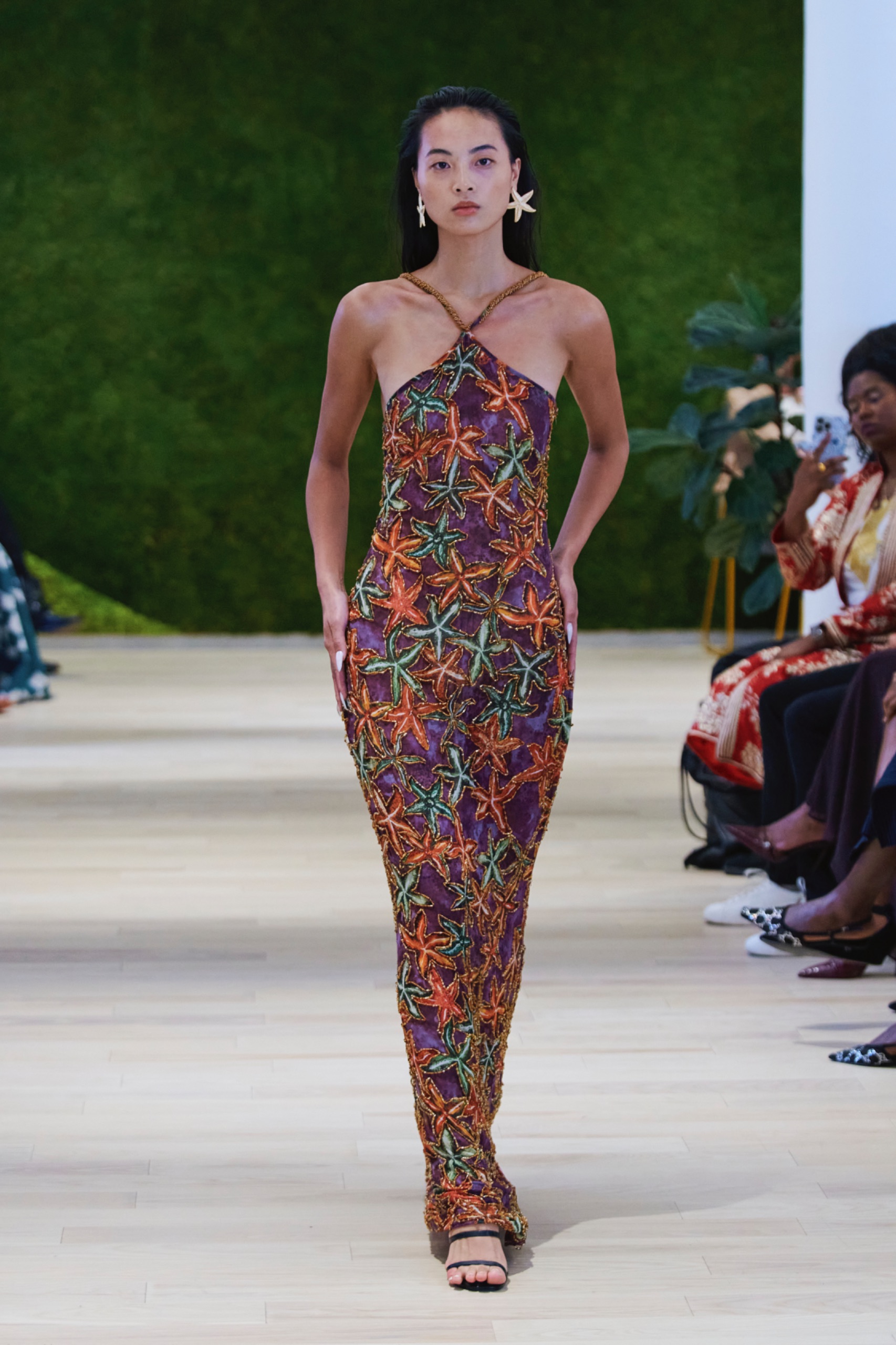 A model walking the runway wearing a long colourful dress.