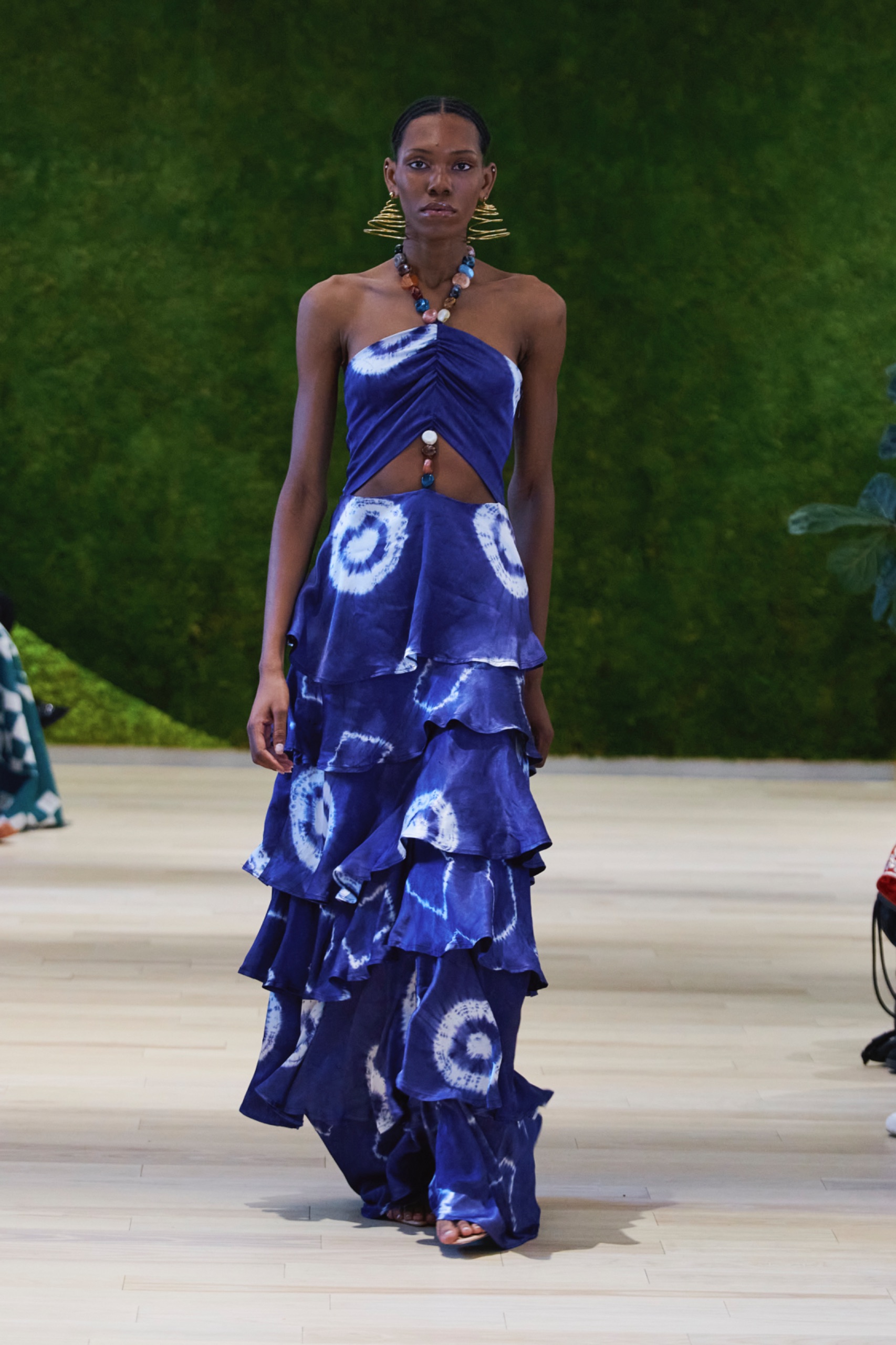 A model walking the runway wearing a blue dress with circle pattern.