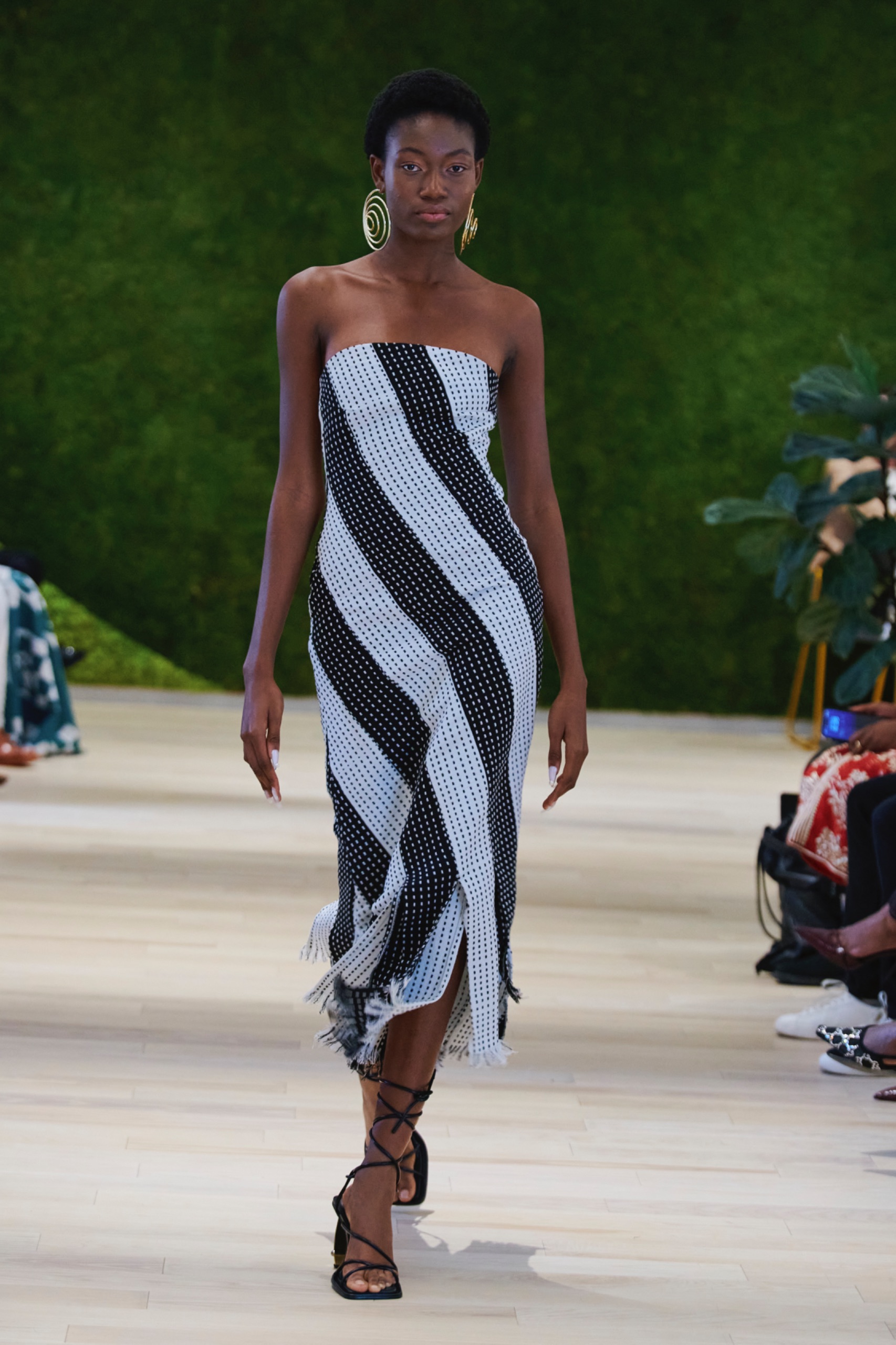 A model walking the runway wearing a black and white striped dress.