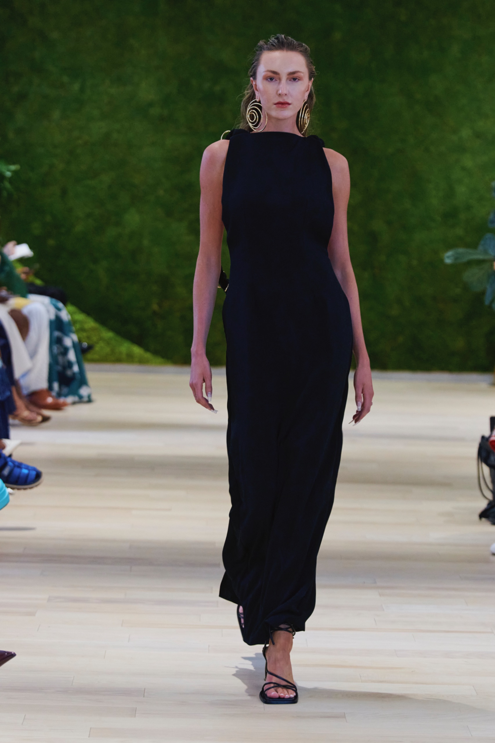 A model walking the runway wearing a long black dress.