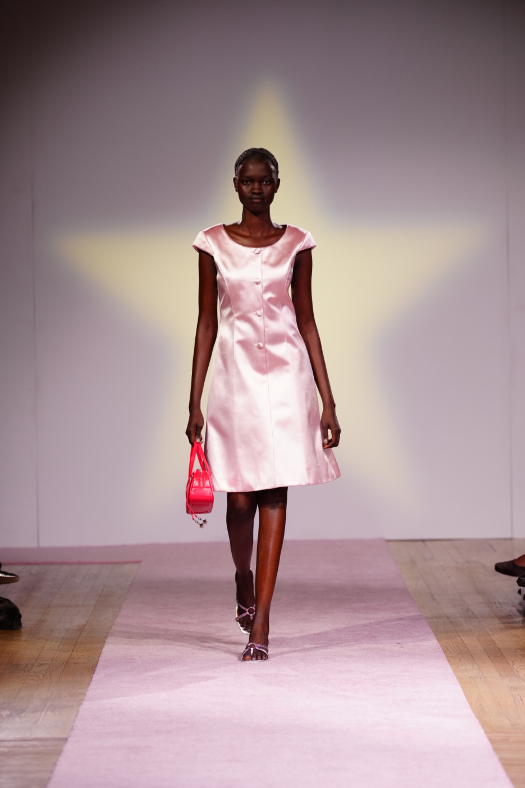 A model walking the runway wearing a pink dress.