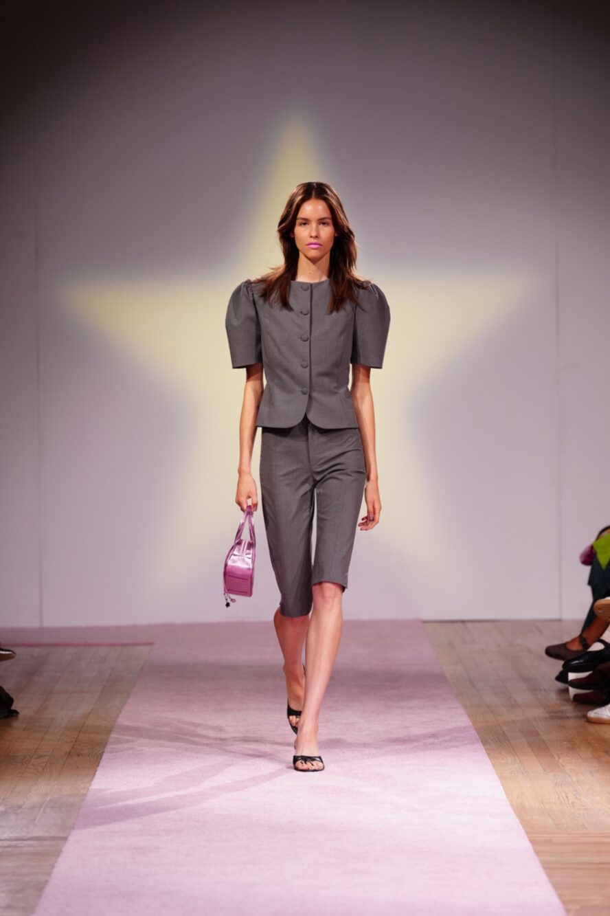 A model walking the runway wearing a grey blazer and skirt.