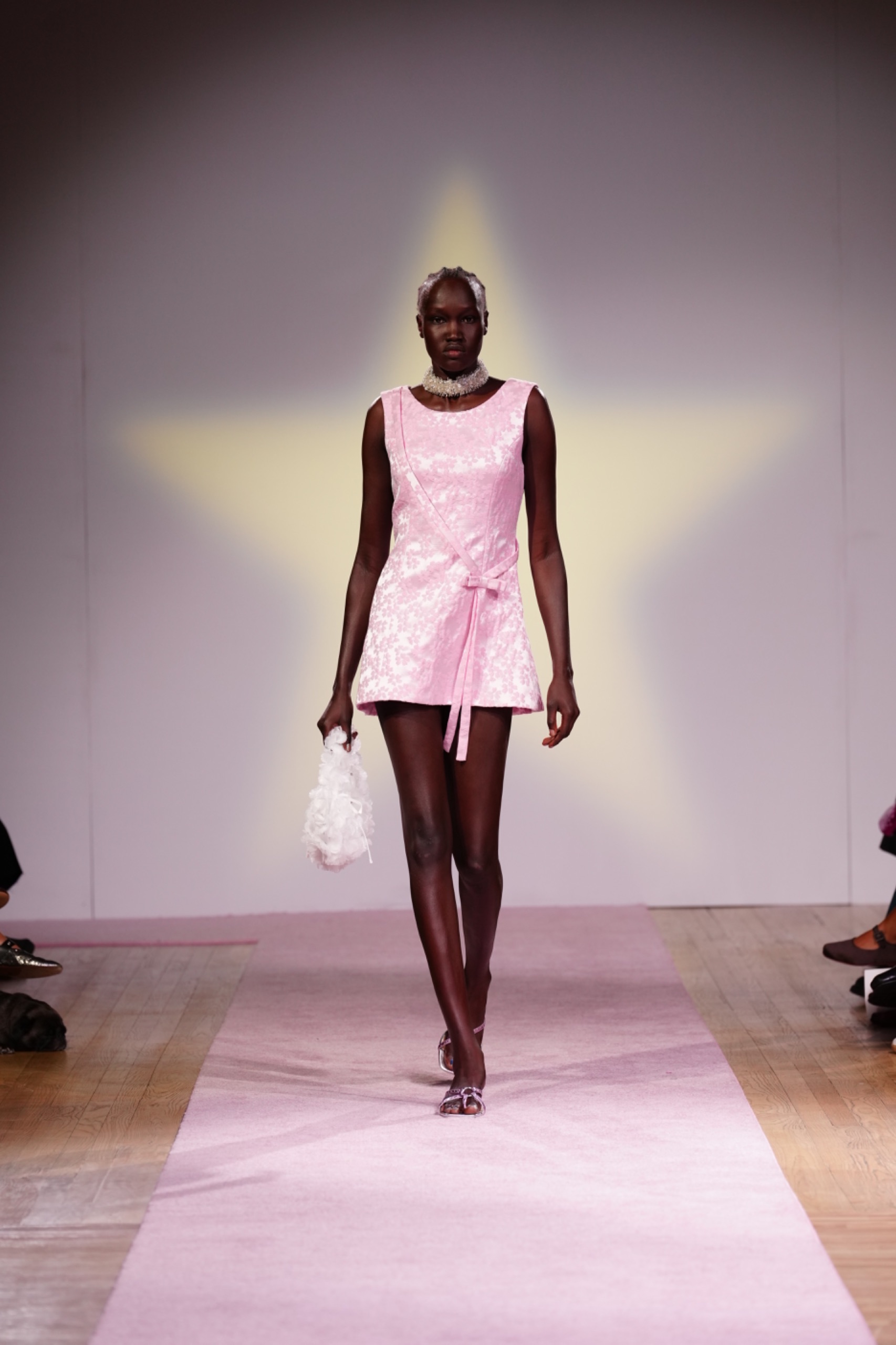 A model walking the runway wearing a pink dress.