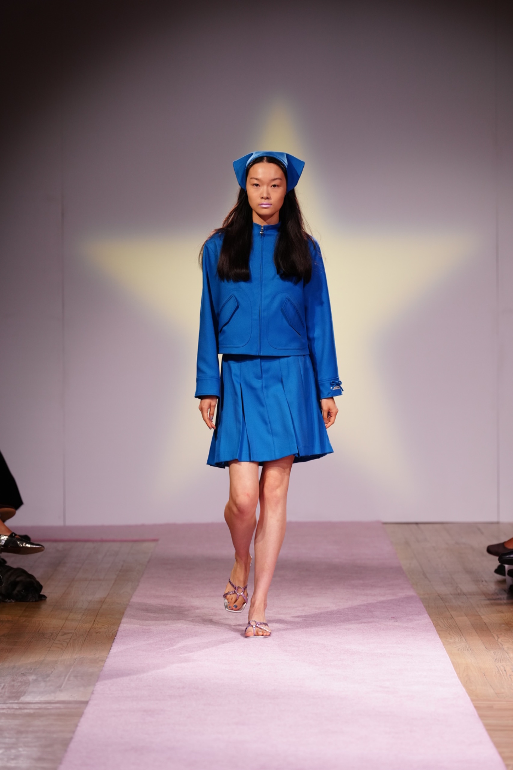 A model walking the runway wearing a blue skirt and top.