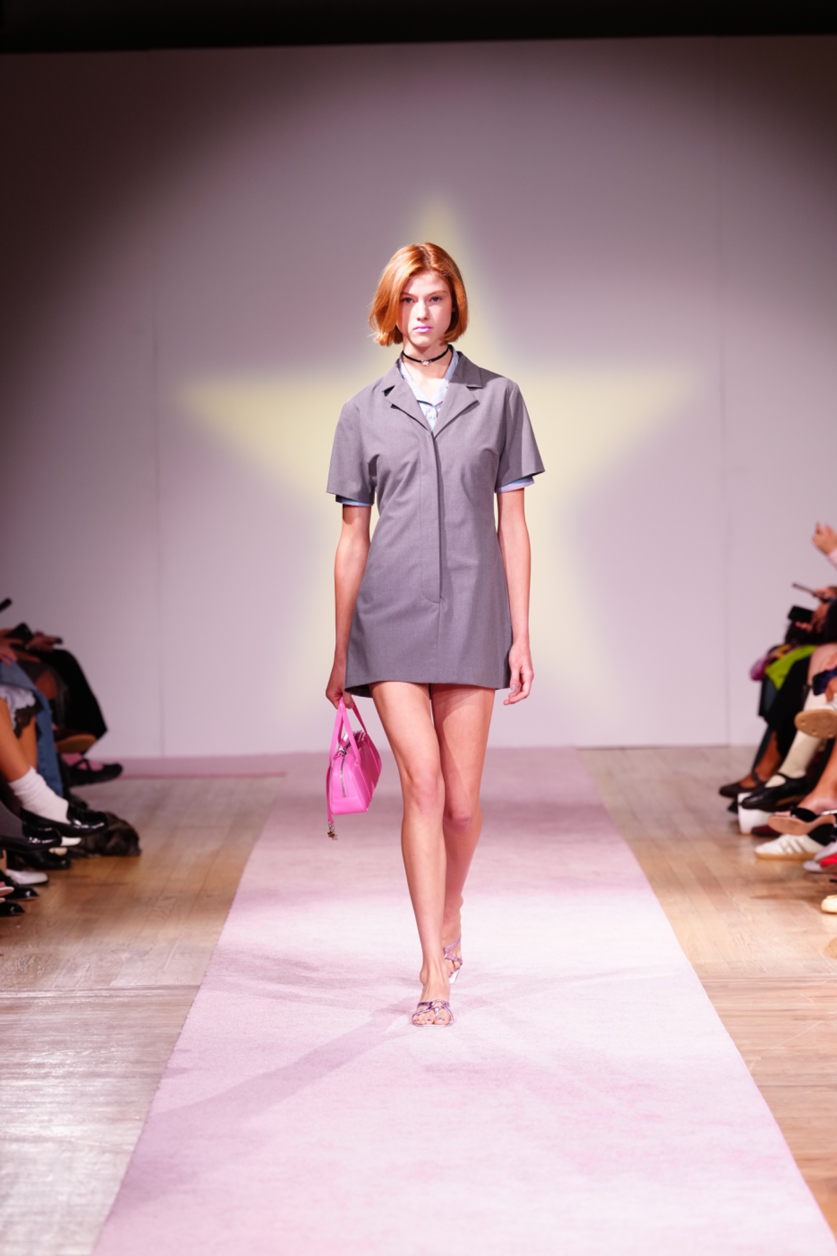 A model walking the runway wearing a grey dress.