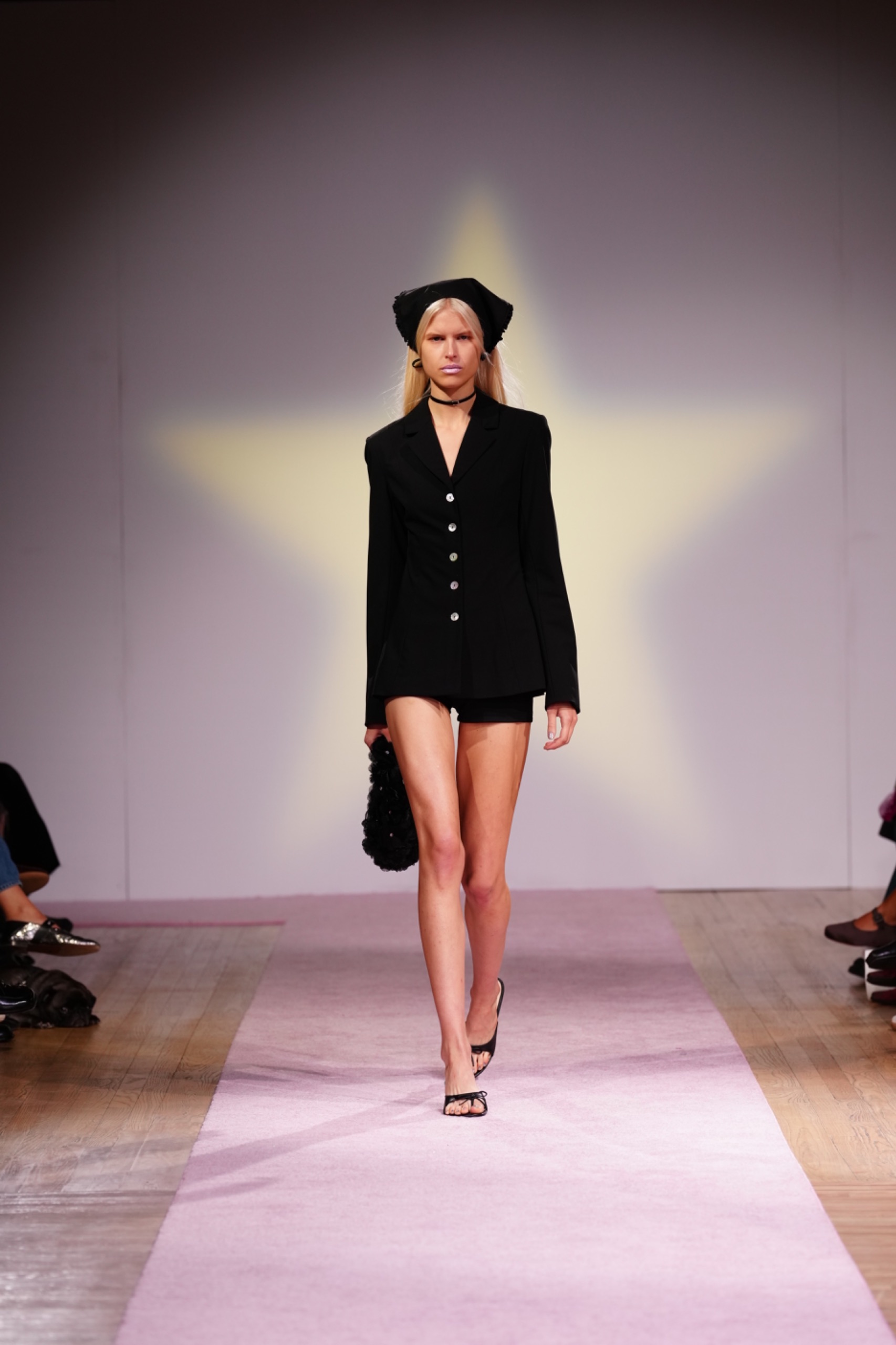 A model walking the runway wearing a black blazer.