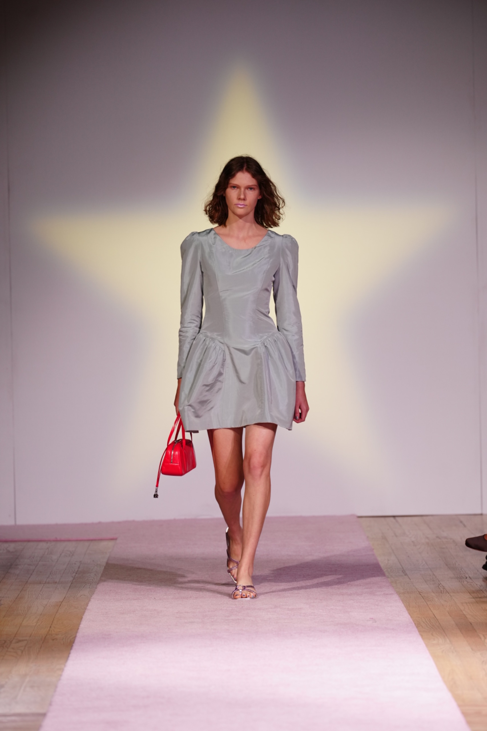 A model walking the runway wearing a grey dress.