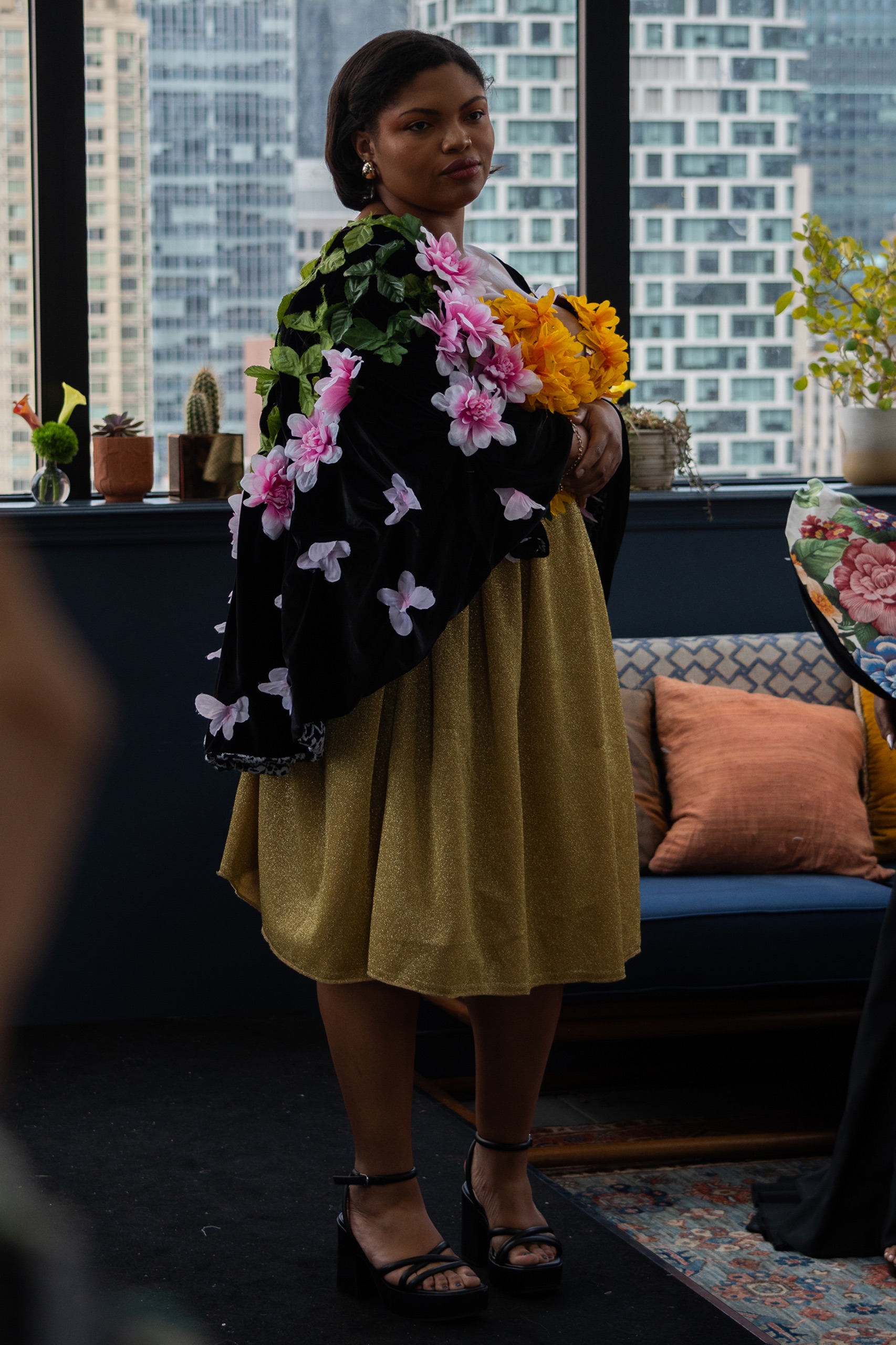 A model wearing an olive dress with floral detailing.