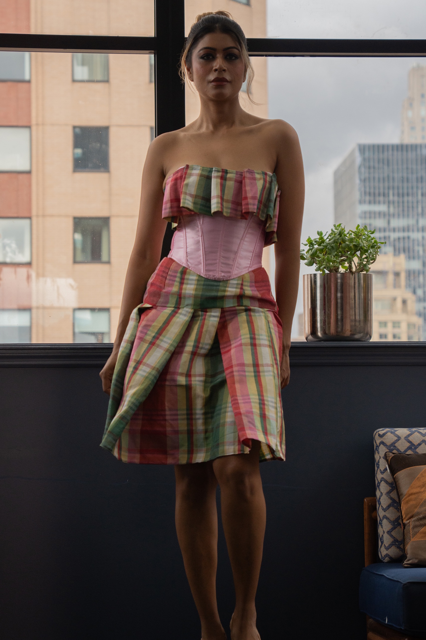 A model wearing a tartan dress with pink belt.