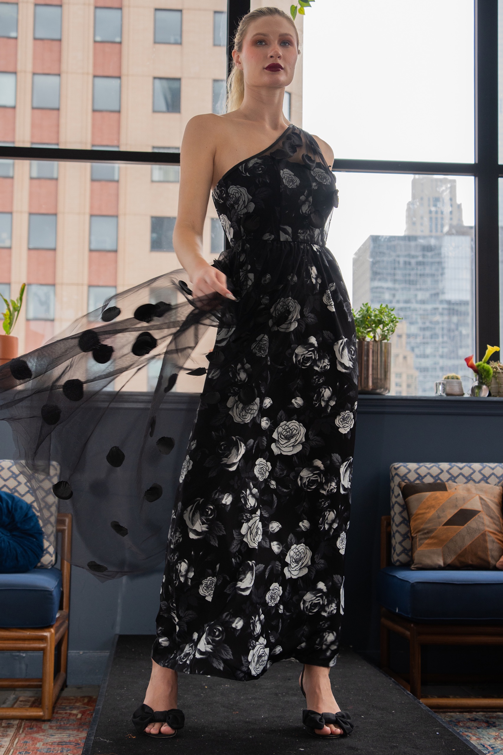 A model wearing a long black floral dress.