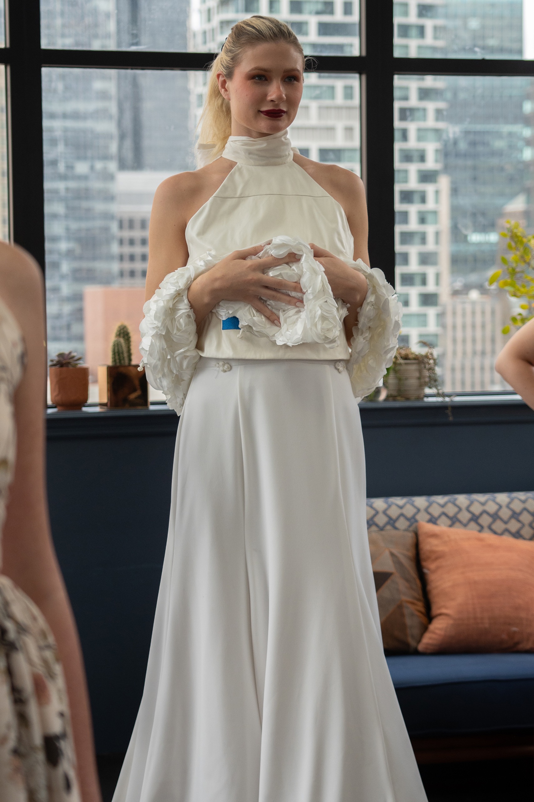 A model wearing a long white dress with blue writing.