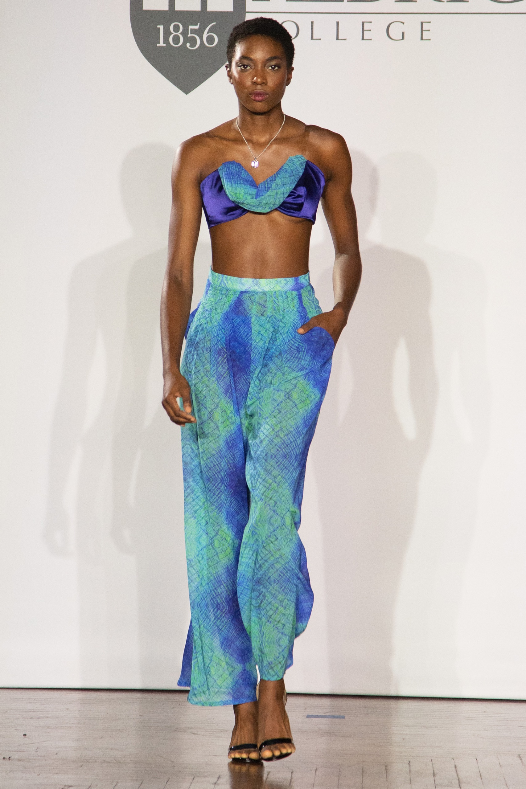 A model walking the runway wearing a blue top with matching trousers.