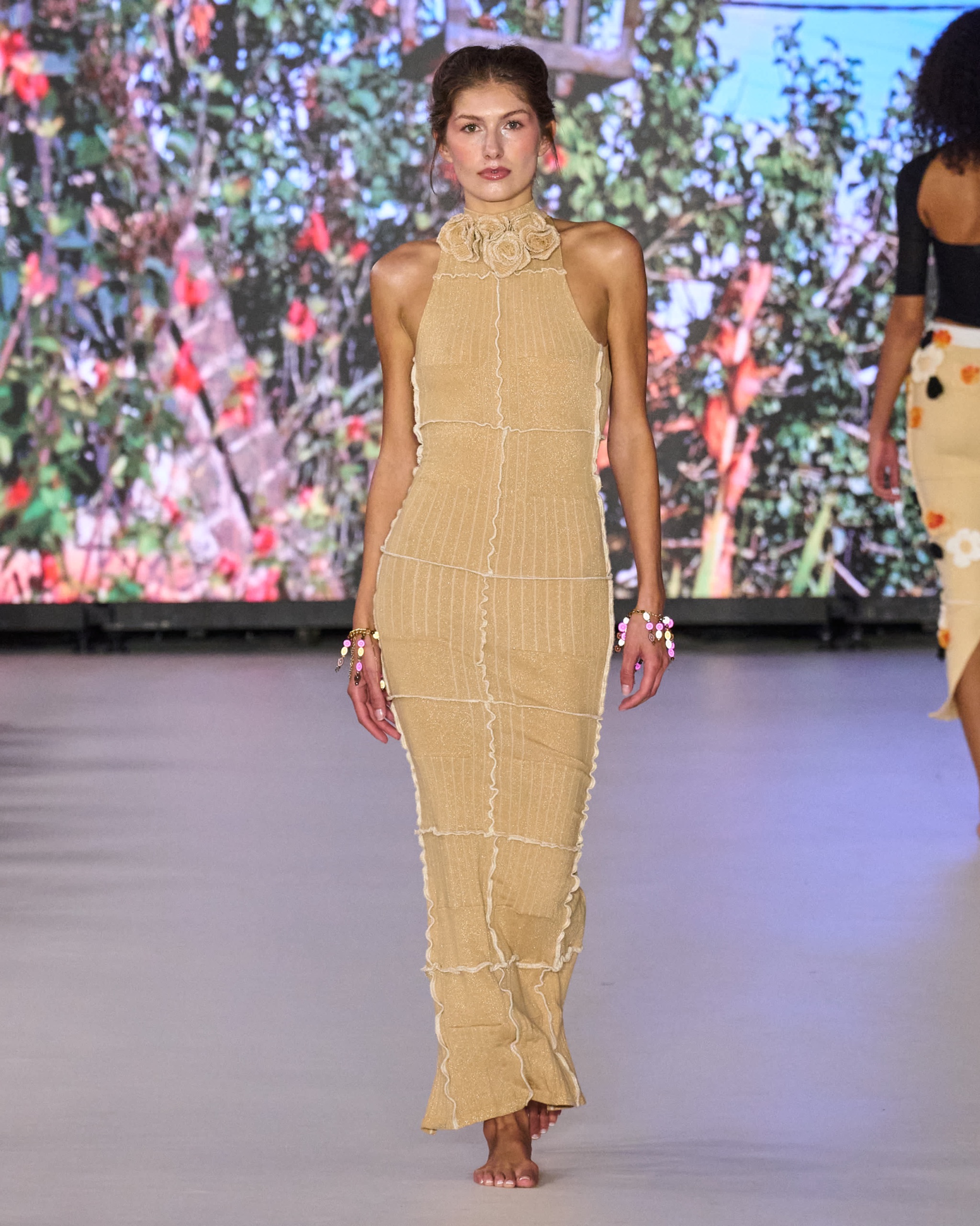 A model walking the runway wearing a long yellow dress.