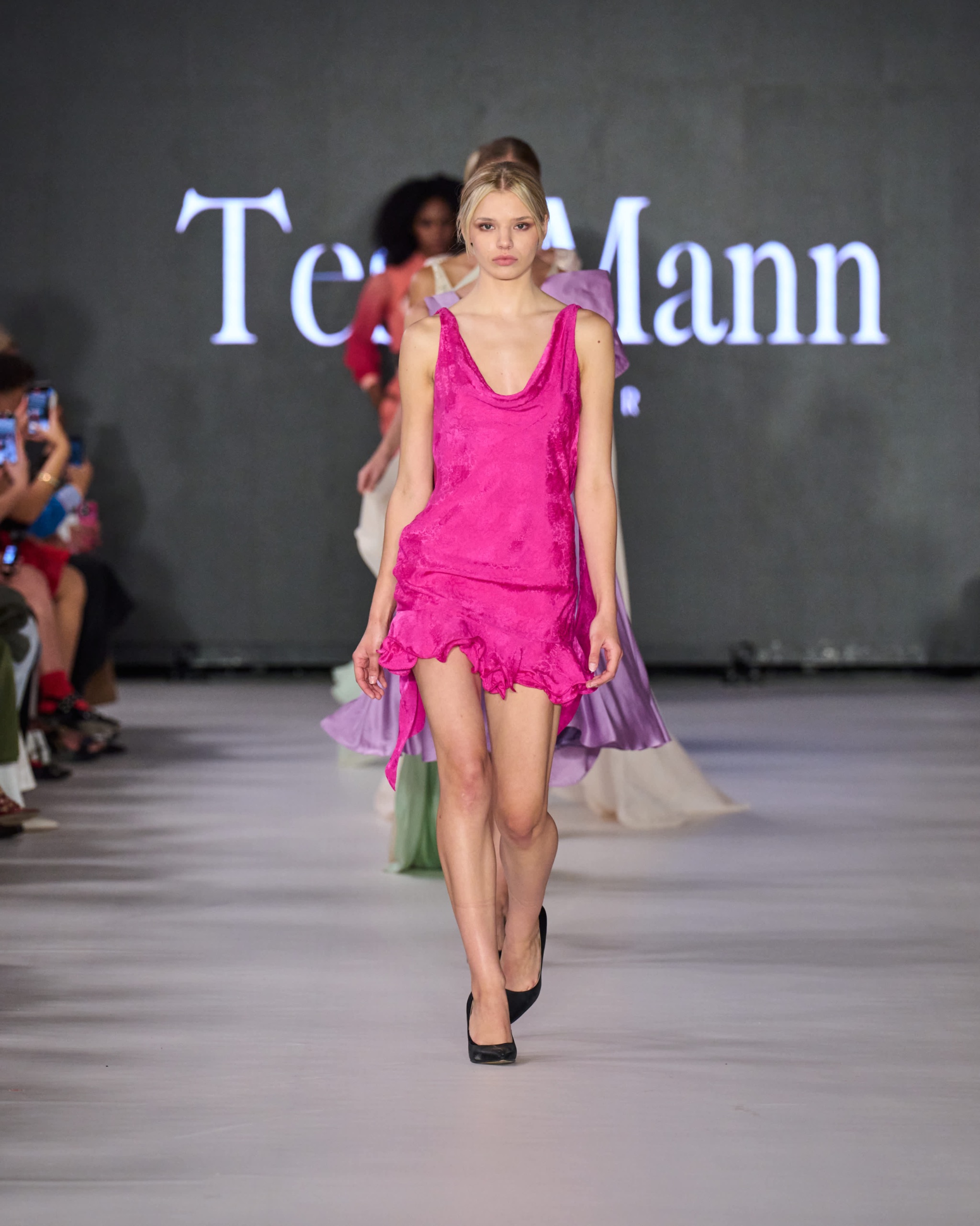 A model walking the runway wearing a pink dress.