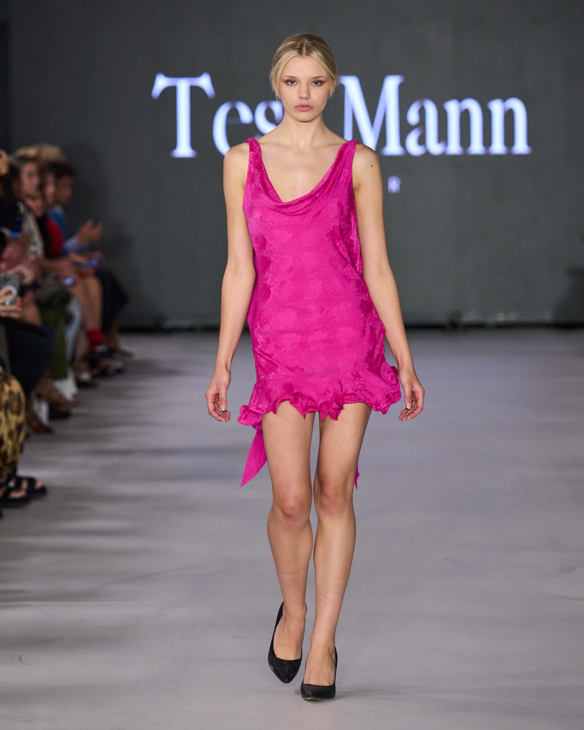 A model walking the runway wearing a pink dress.