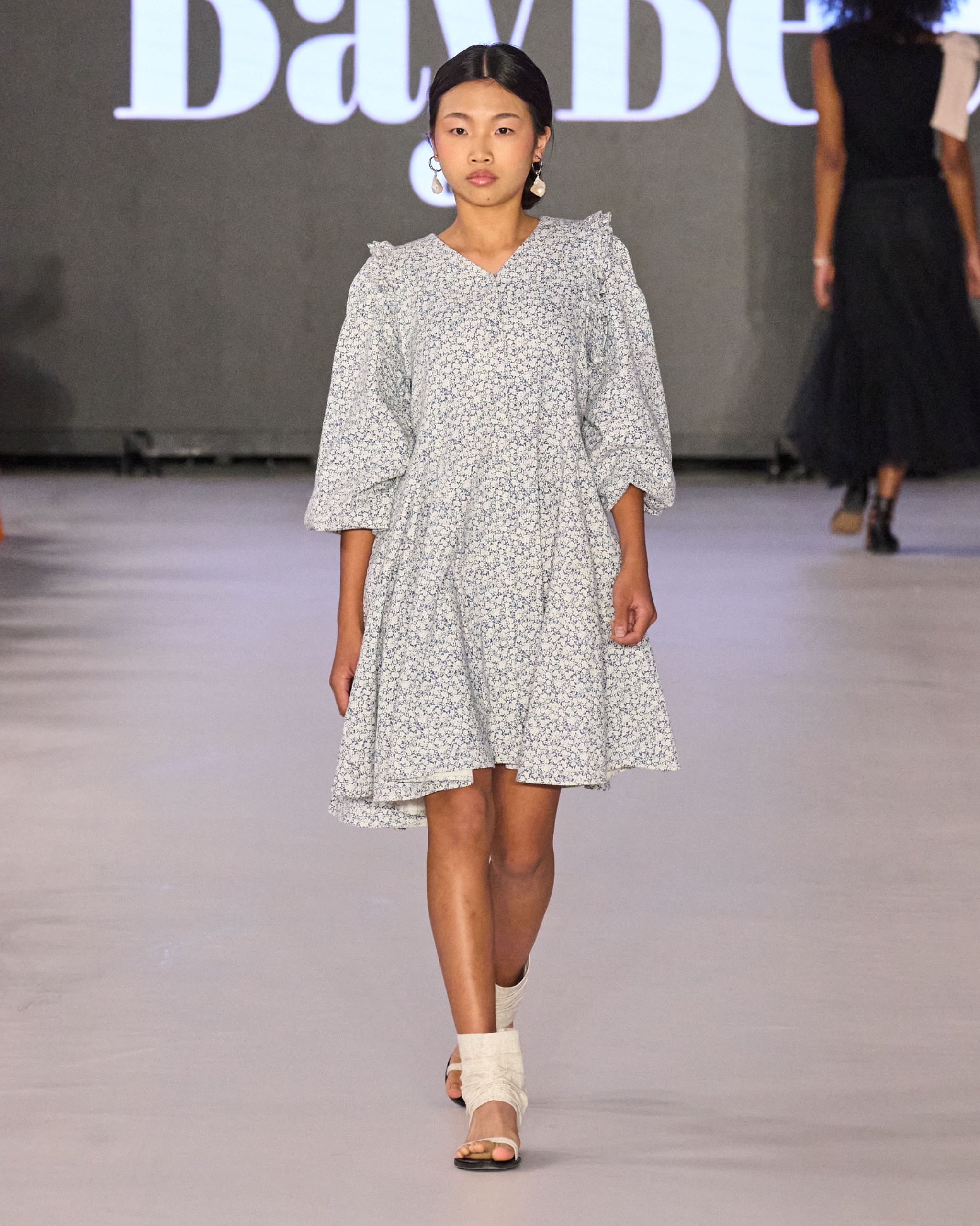 A model walking the runway in a grey dress.