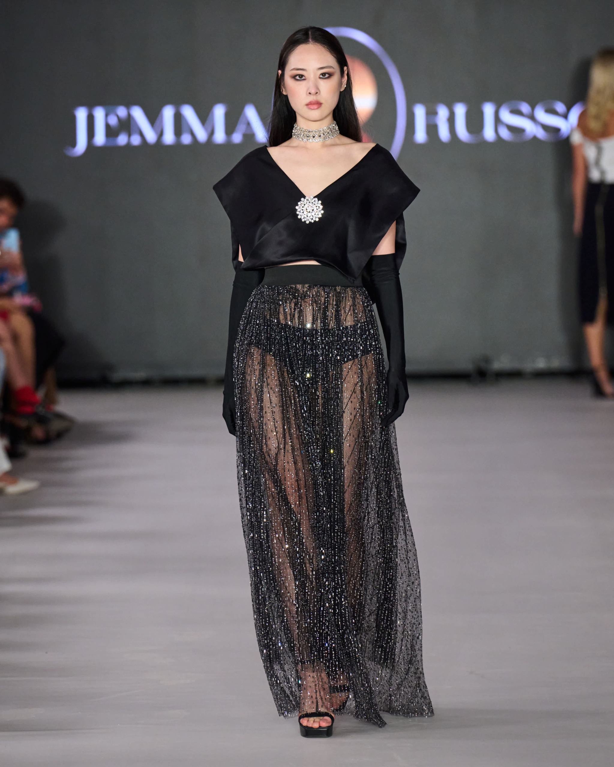 A model walking the runway wearing a long black gown with long black sleeves.