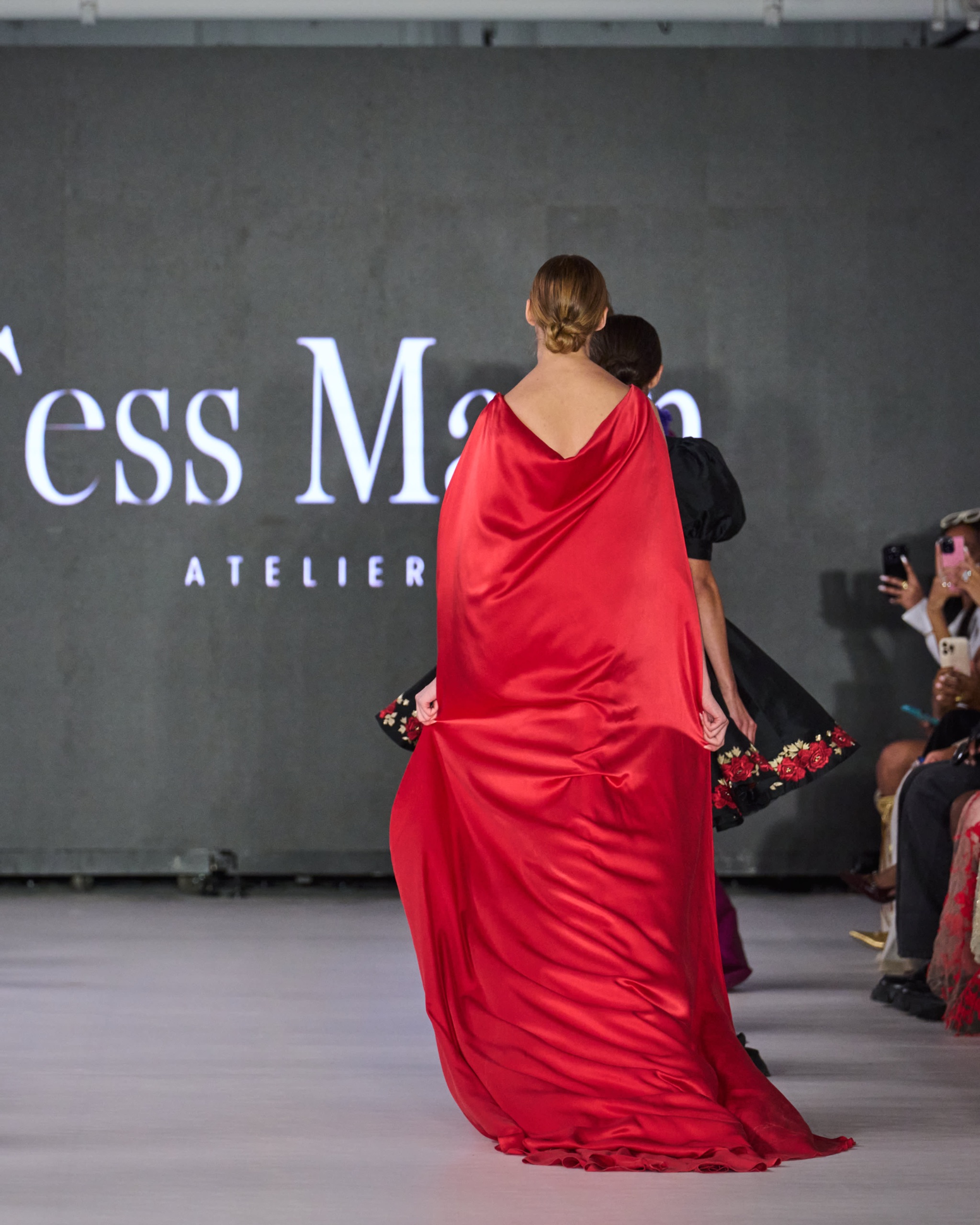 A model walking the runway wearing a red gown.