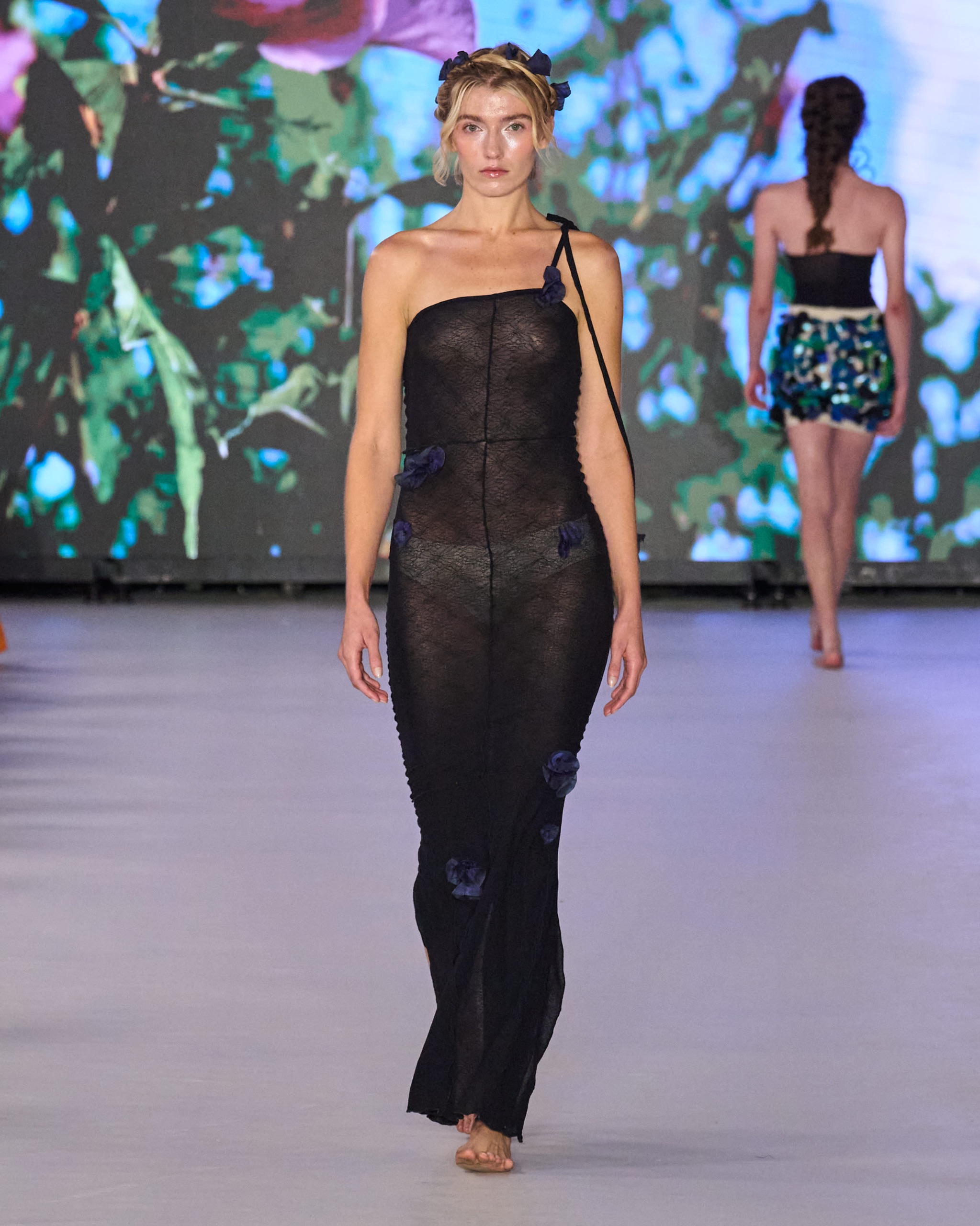 A model walking the runway wearing a long black dress.