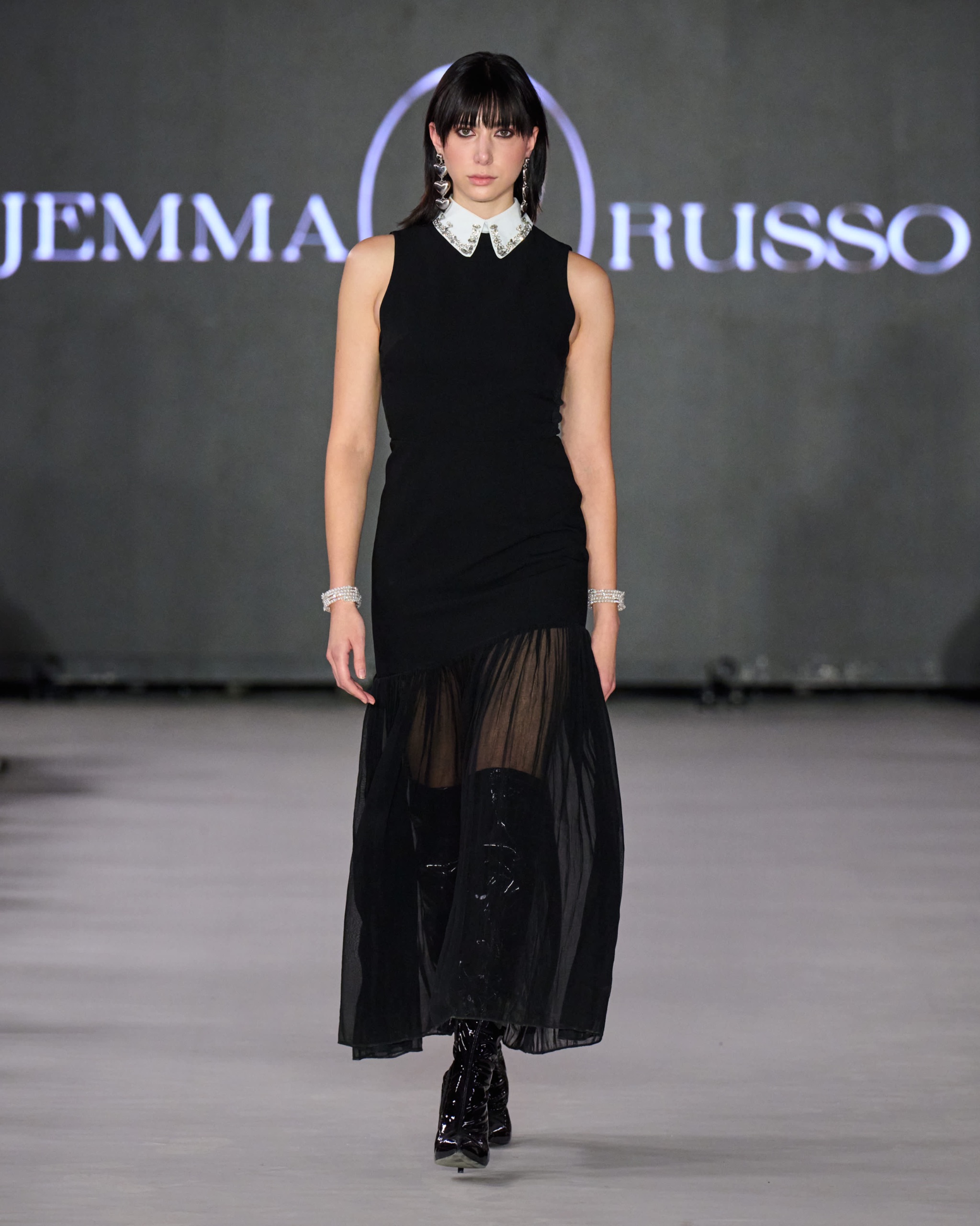 A model walking on the runway wearing a long black dress.