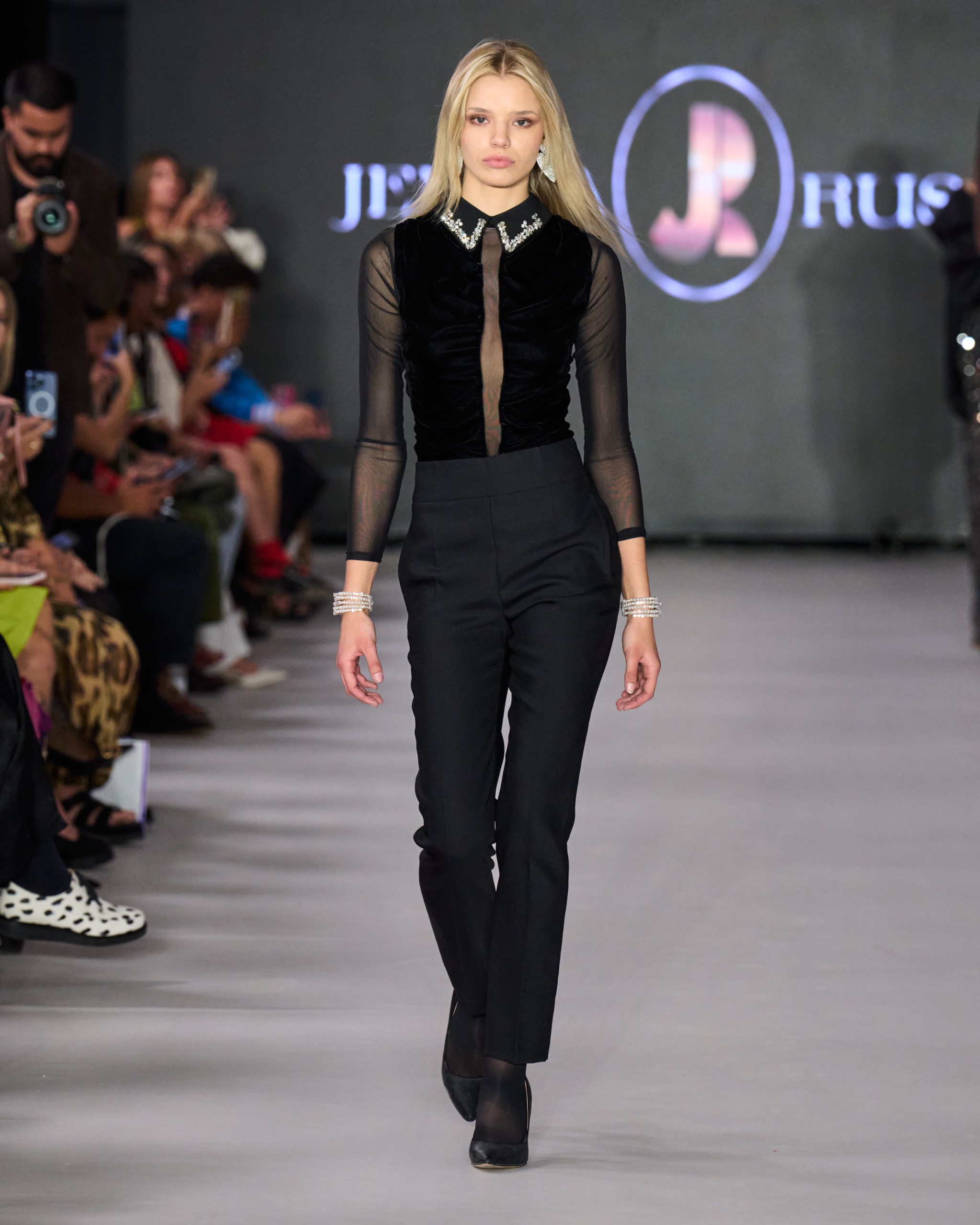 A model walking on the runway wearing a long-sleeved black top and black trousers.