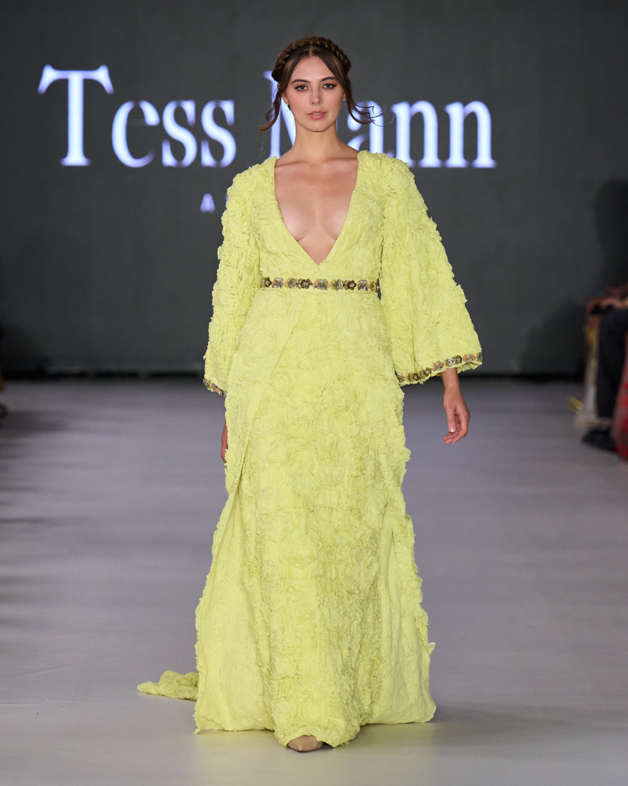 A model walking on the runway wearing a long yellow dress.