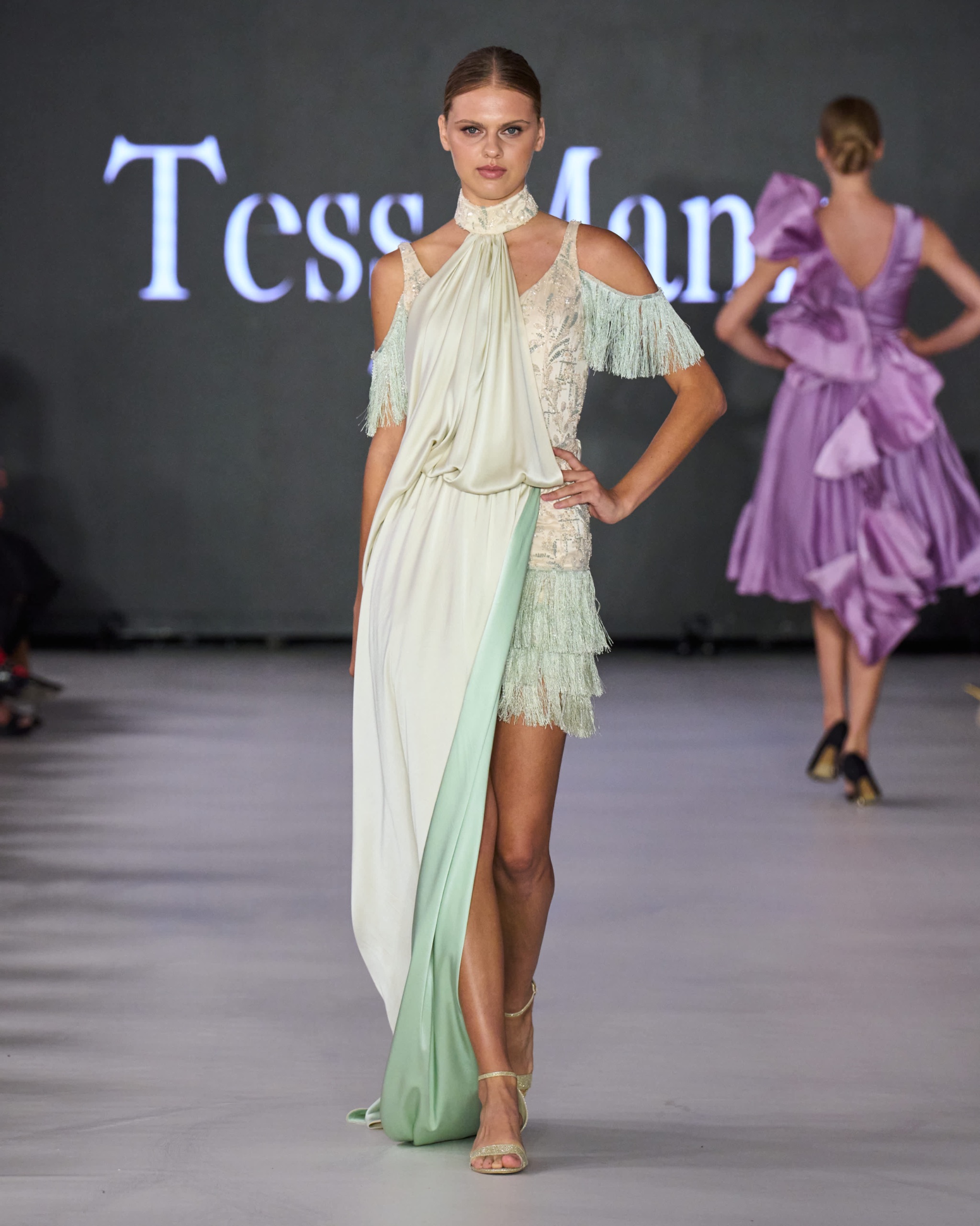 A model walking the runway wearing a long green dress.