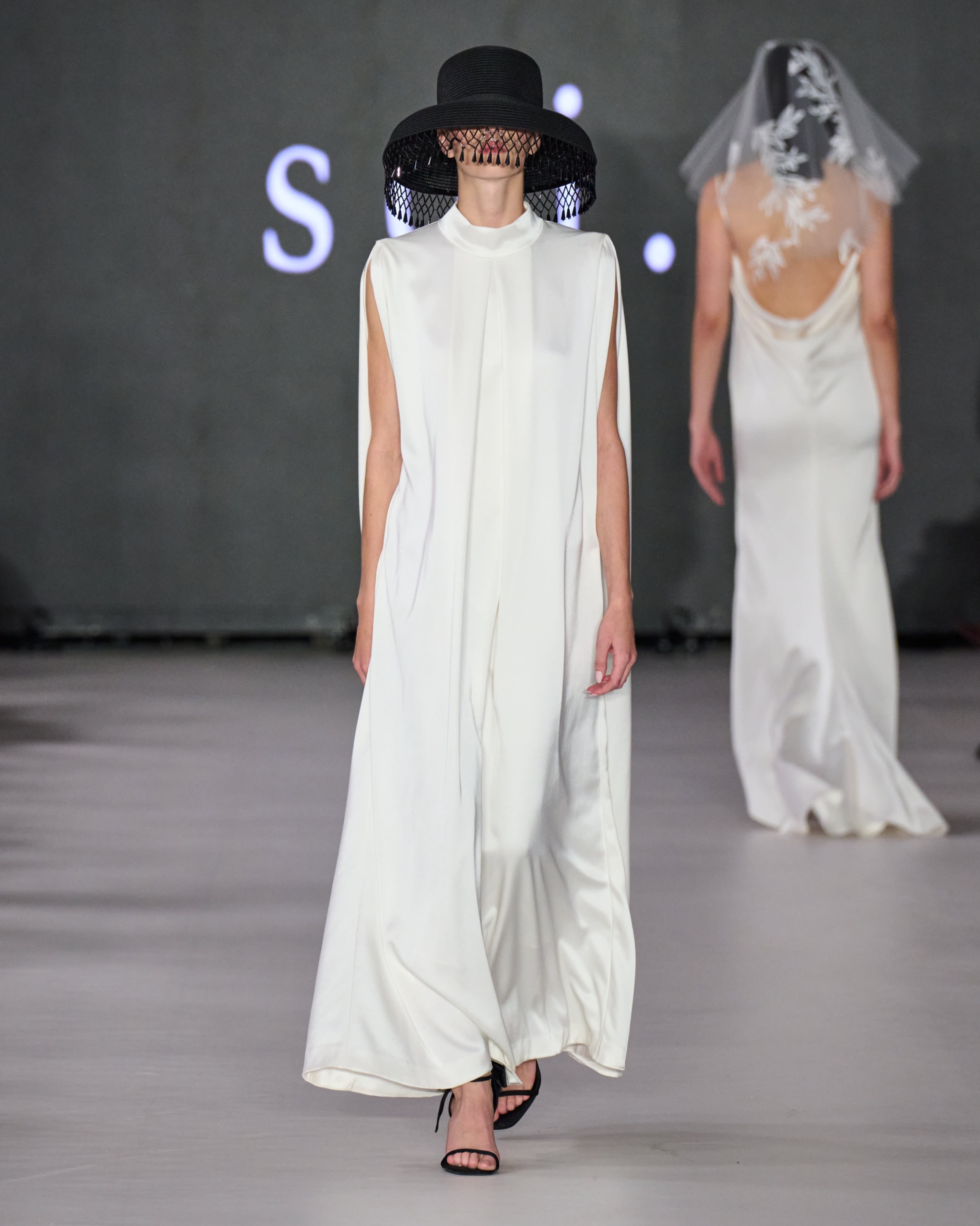 A model walking the runway wearing a white dress.