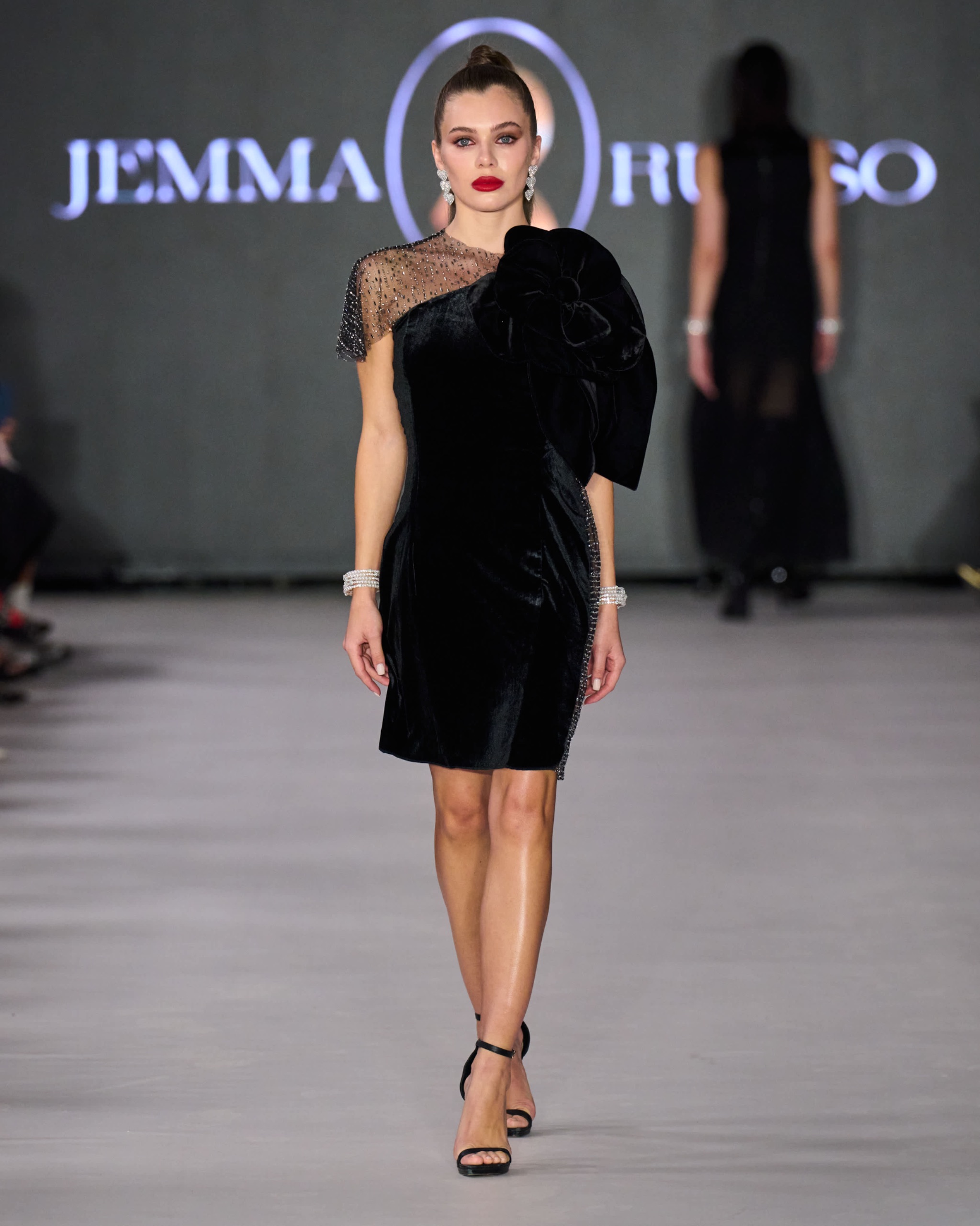 A model walking the runway wearing a black dress.