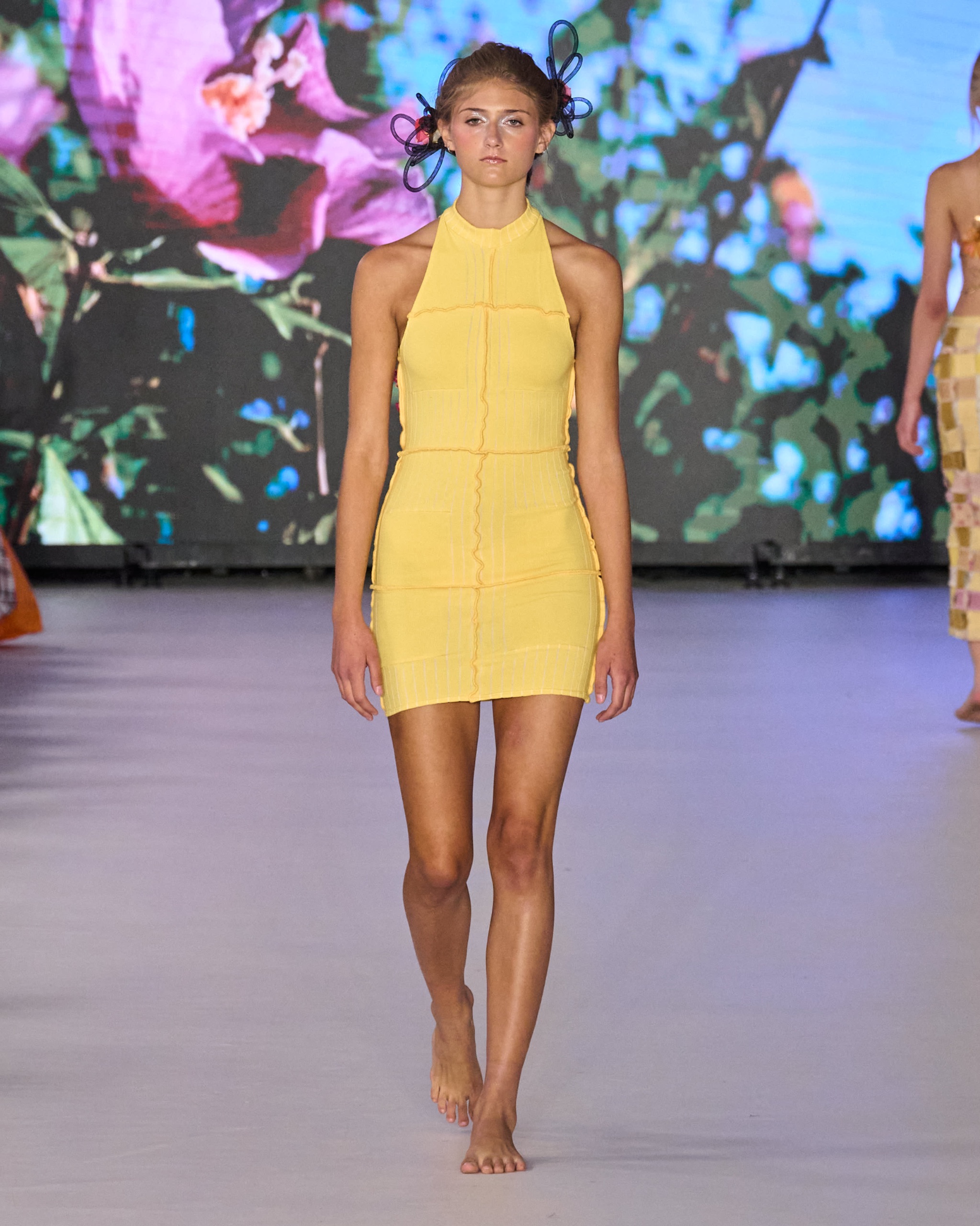 A model walking the runway wearing a yellow dress.