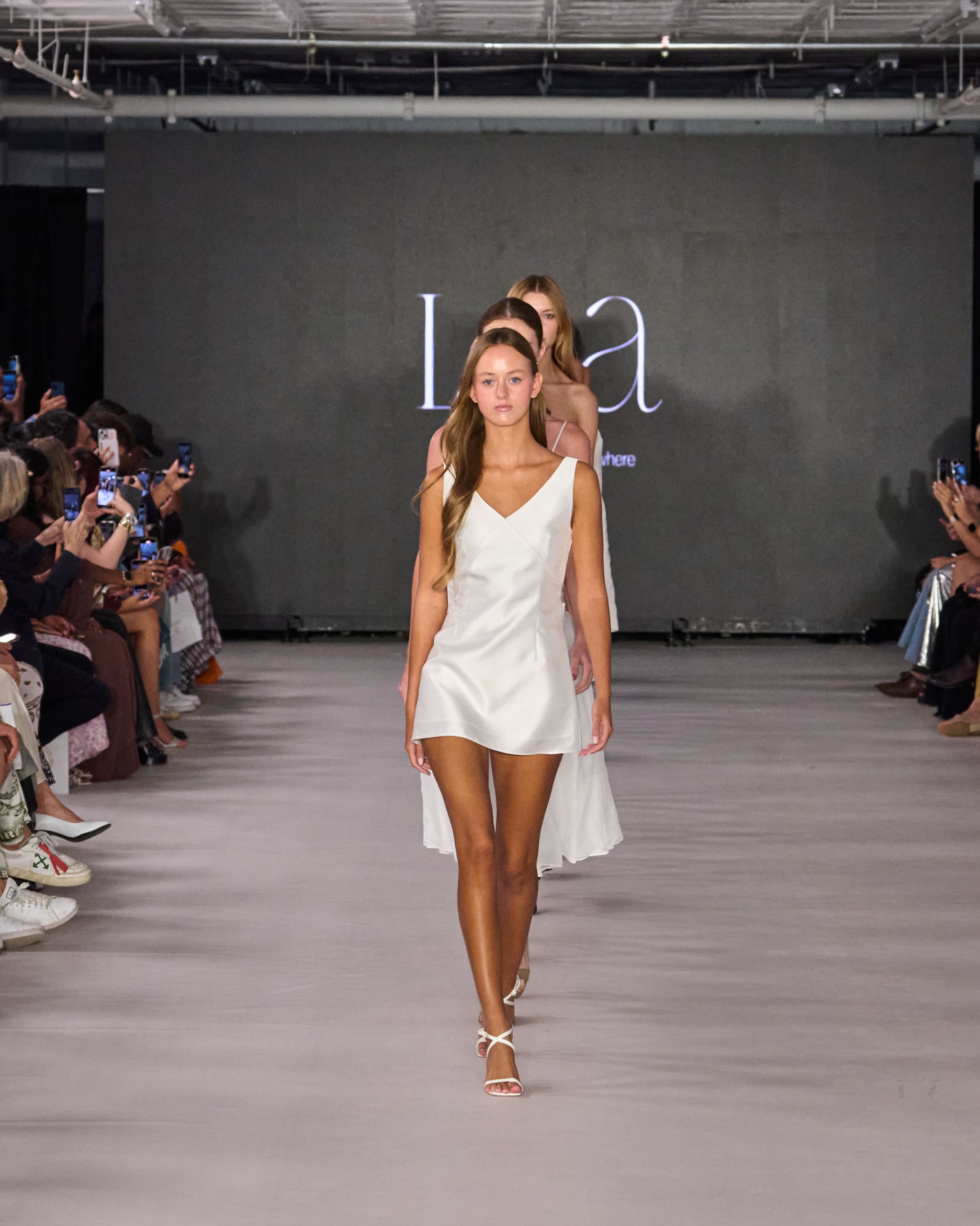 A model walking the runway wearing a white dress.