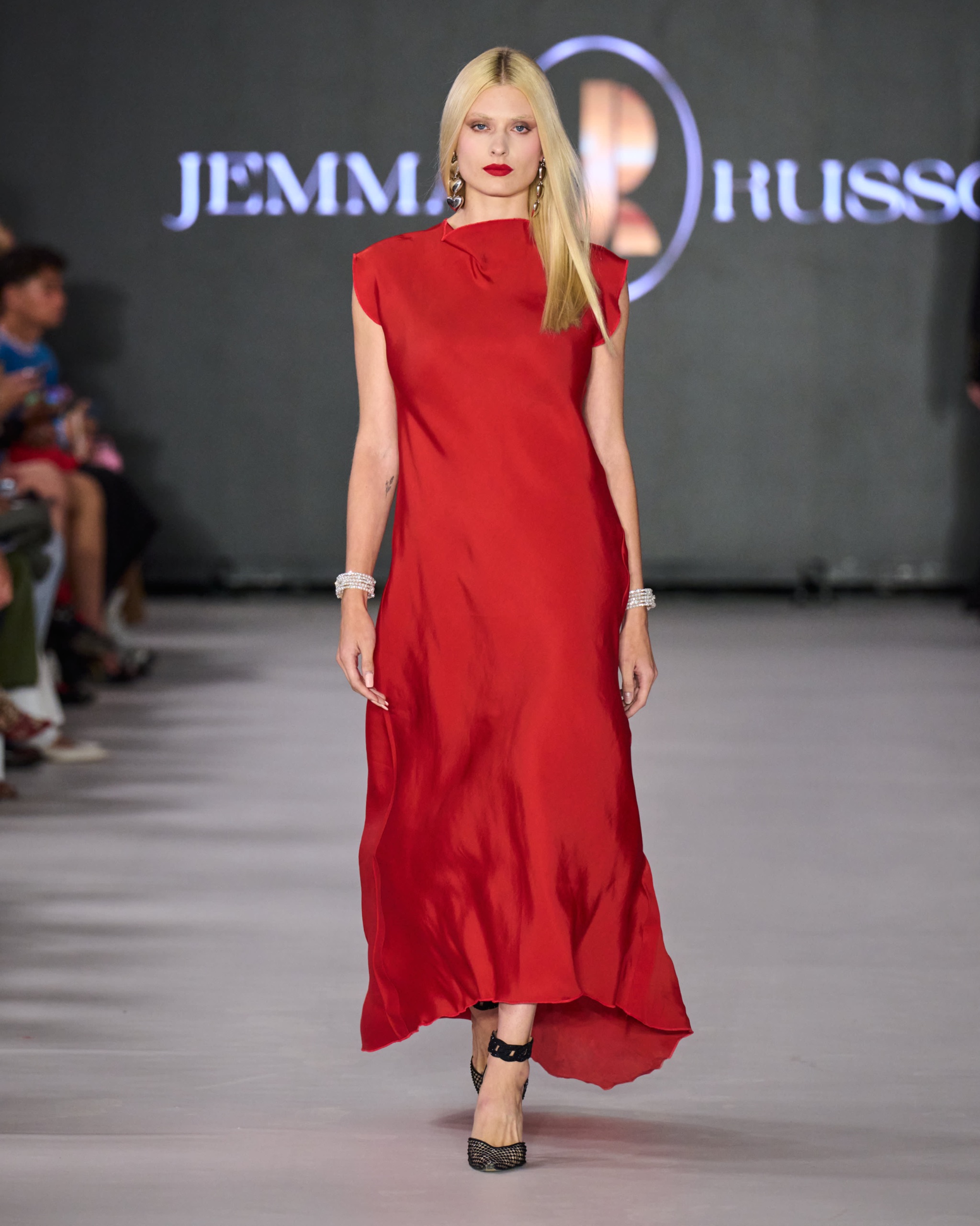 A model walking the runway wearing a long red dress.